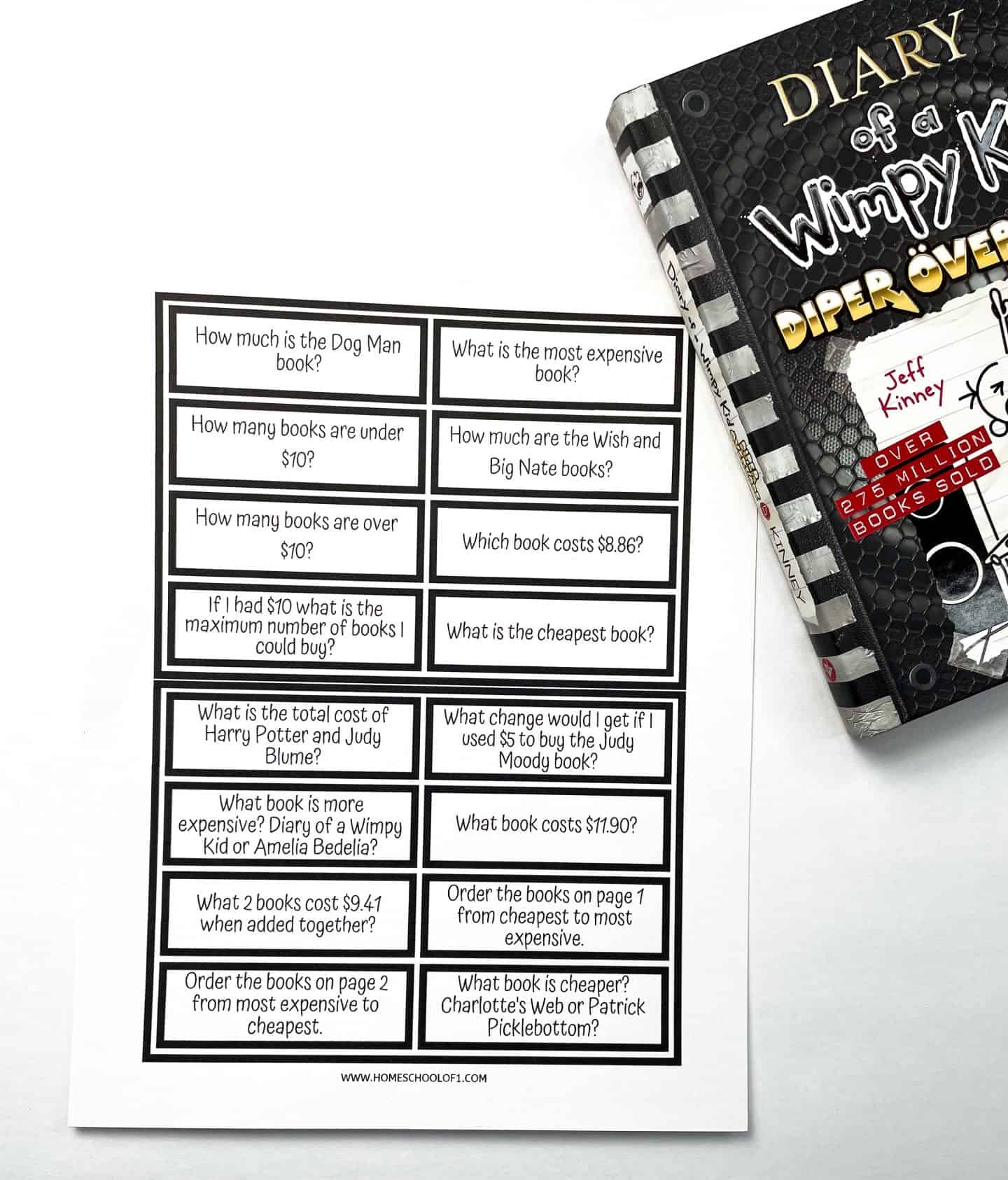 Black and white worksheet with 18 math word problems related to book prices, designed to pair with a pretend bookstore shopping activity. Questions include comparing book prices, calculating change, identifying the most and least expensive books, and solving word problems involving addition and budgeting with a $10 limit. A copy of Diary of a Wimpy Kid is partially visible beside the worksheet.