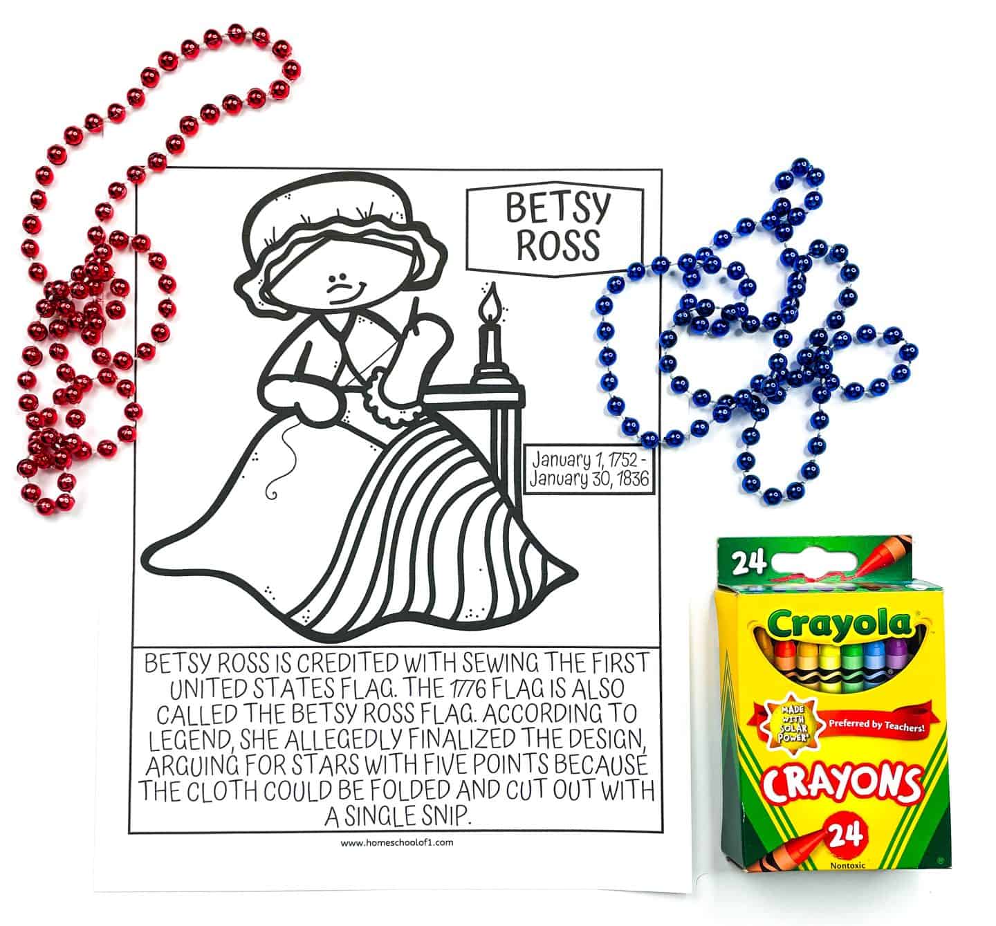 A black-and-white coloring page featuring Betsy Ross sewing the first American flag. The caption below describes how she is credited with finalizing the design of the 1776 flag, arguing for five-pointed stars because they could be cut with a single snip. Red and blue bead necklaces are arranged on either side of the page, and a 24-pack of Crayola crayons is placed to the right.