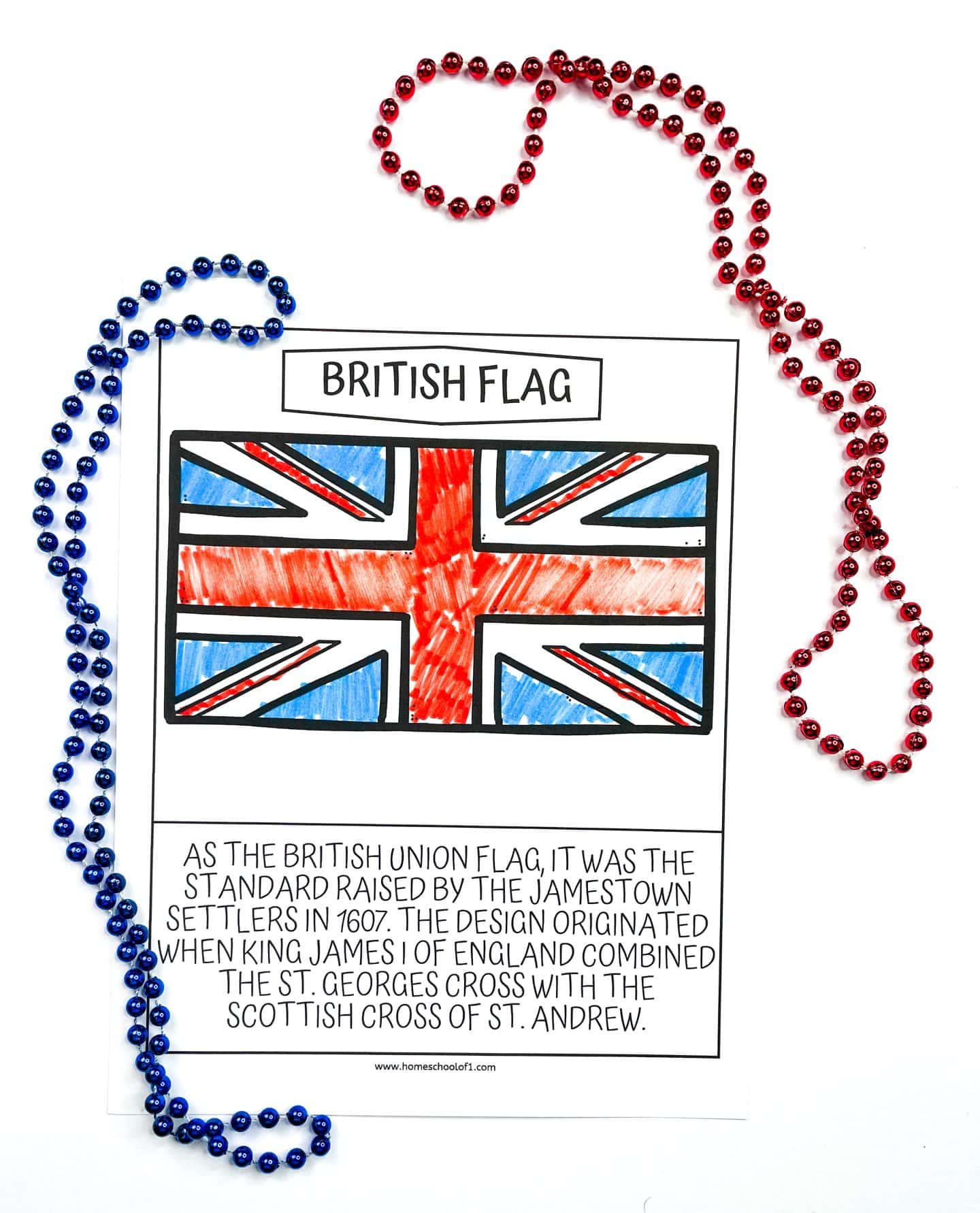 A coloring worksheet featuring the British Union flag, colored with red, blue, and black markers. Below the flag, a caption explains its history, stating it was the standard raised by the Jamestown settlers in 1607 and was designed by combining the St. George's Cross with the Scottish Cross of St. Andrew. Blue and red bead necklaces are placed around the sheet for decoration.