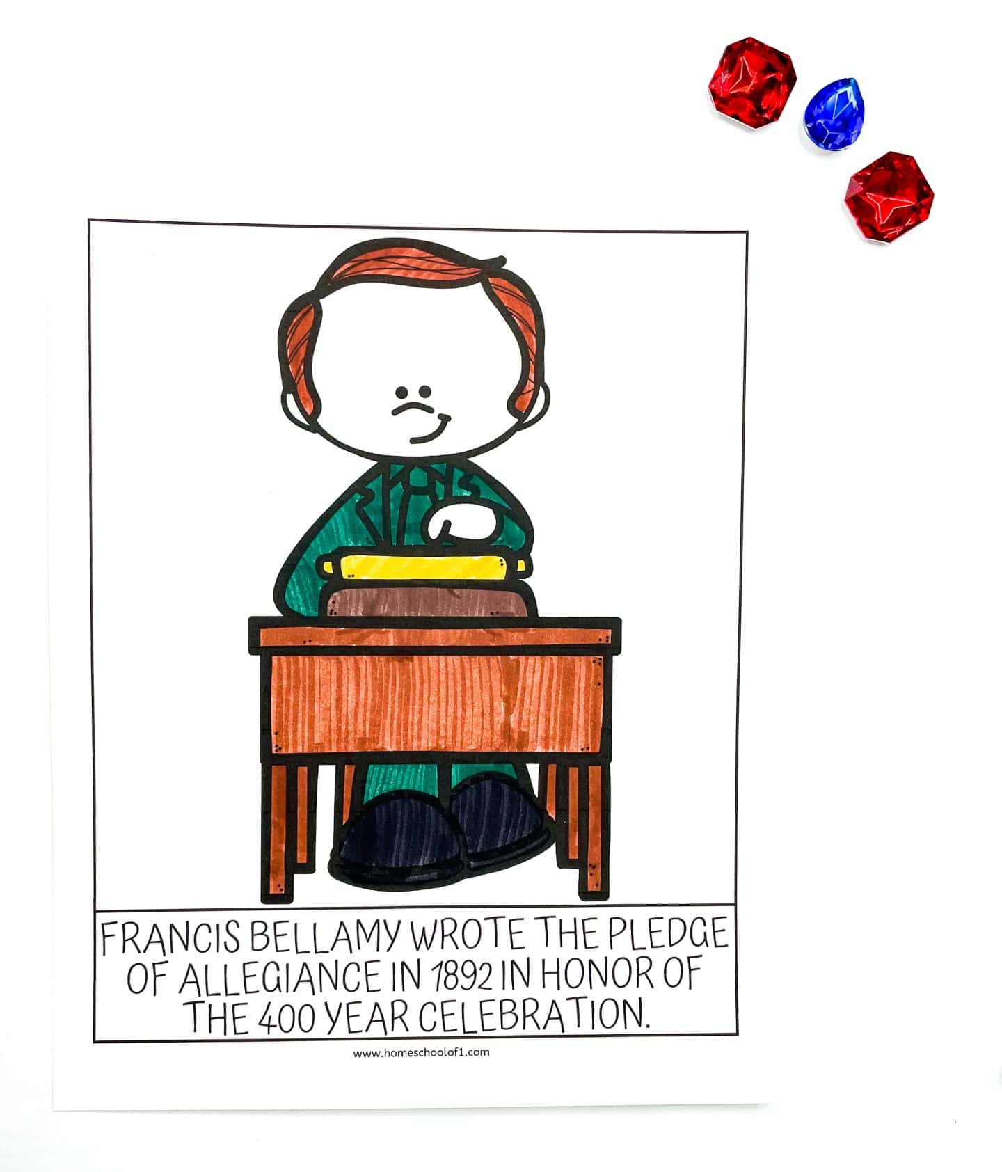 Coloring page of Francis Bellamy seated at a wooden desk with a book, wearing a green suit. The caption reads, “Francis Bellamy wrote the Pledge of Allegiance in 1892 in honor of the 400 year celebration.” Three red and blue plastic gem decorations sit in the top right corner of the white background.