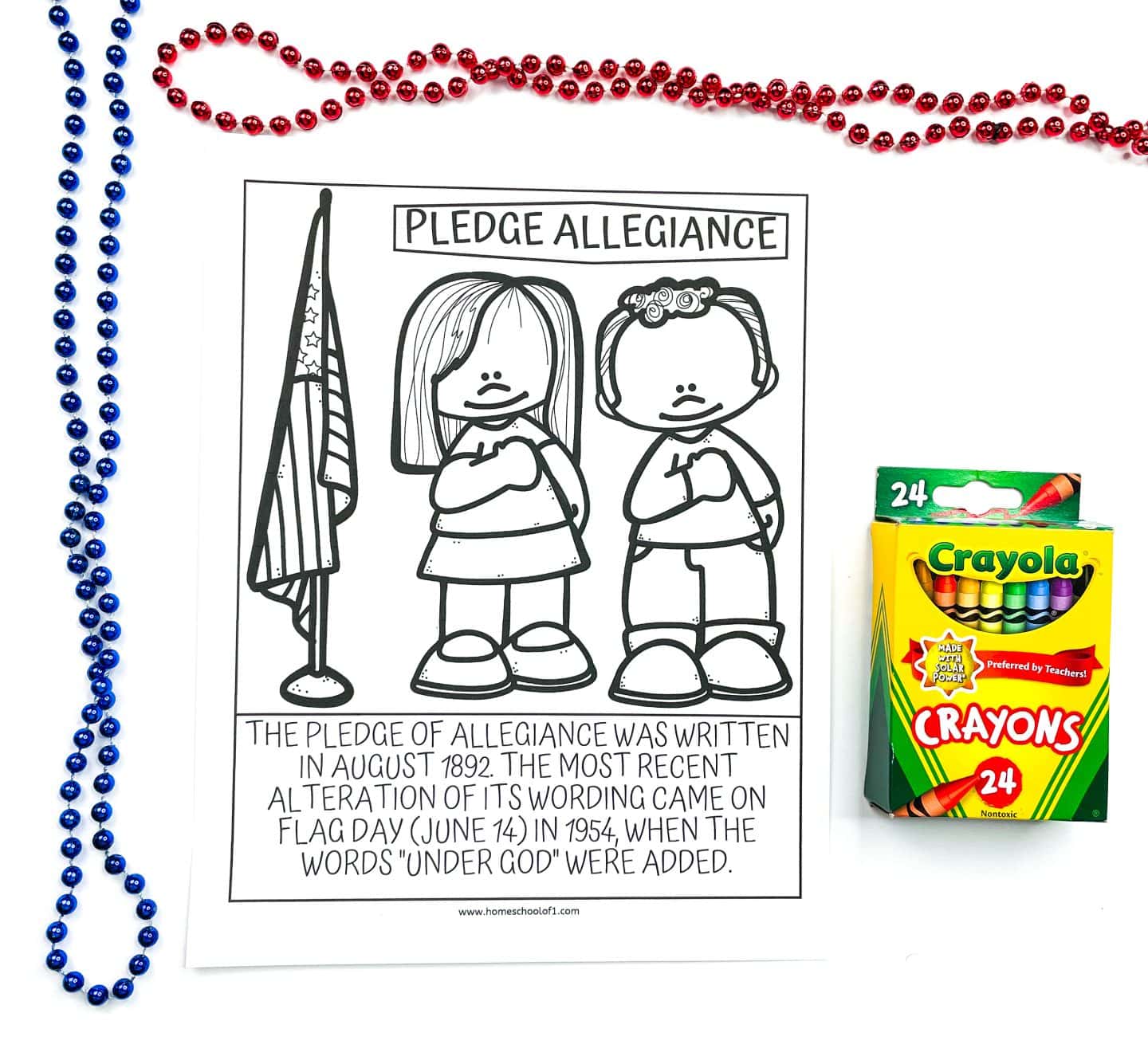 A black-and-white coloring page titled “Pledge Allegiance” showing a girl and boy standing with hands over their hearts next to an American flag. The caption below states the Pledge of Allegiance was written in August 1892, and the most recent alteration was made on Flag Day in 1954, adding the words “under God.” Red and blue beaded necklaces and a 24-pack of Crayola crayons are placed beside the page.