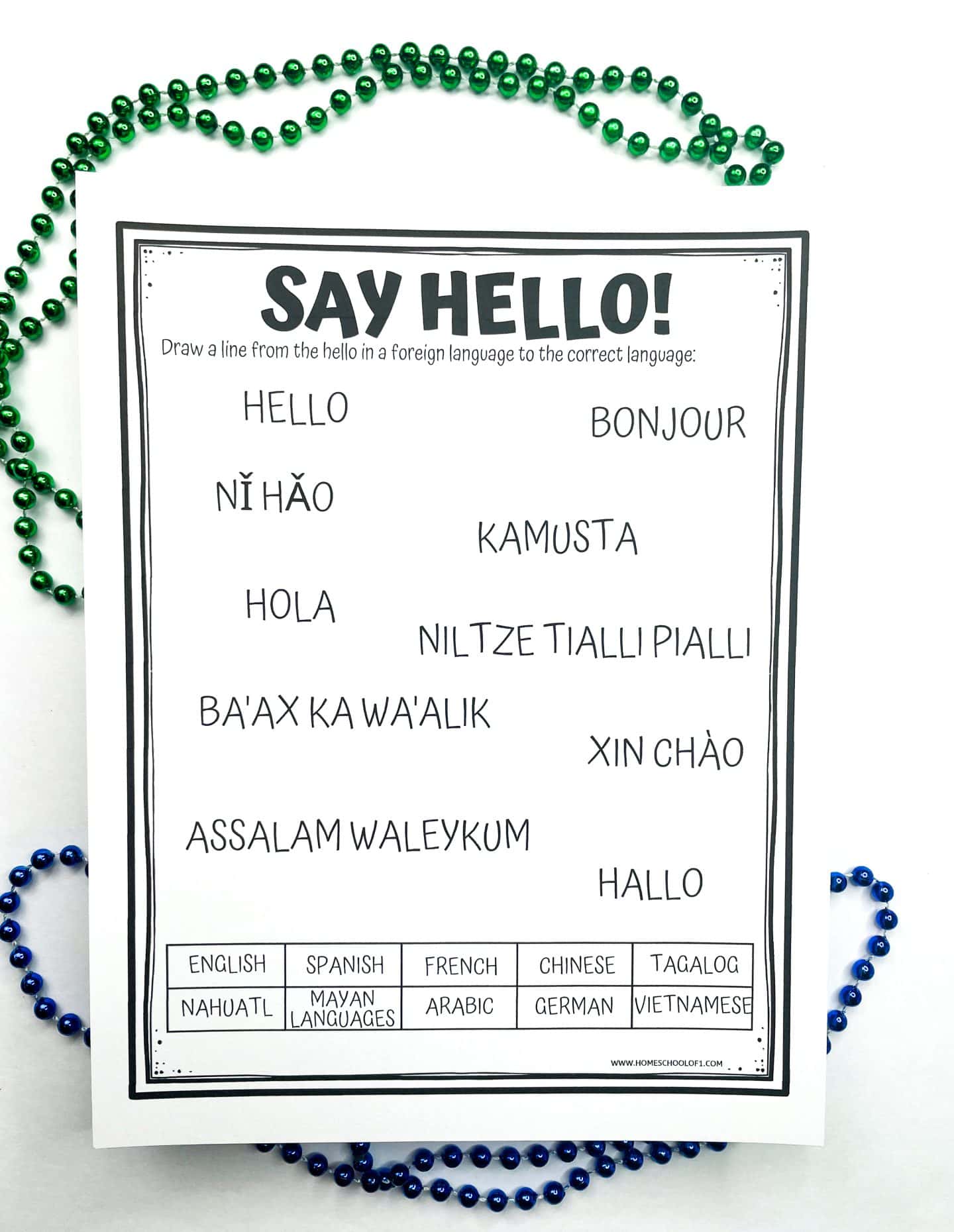 Printable worksheet titled "Say Hello!" asking students to draw lines connecting greetings in different languages (e.g., "Bonjour", "Ni Hao", "Kamusta") to their corresponding language from a list including English, Spanish, French, Chinese, Tagalog, and more. The sheet is surrounded by green and blue beaded necklaces.