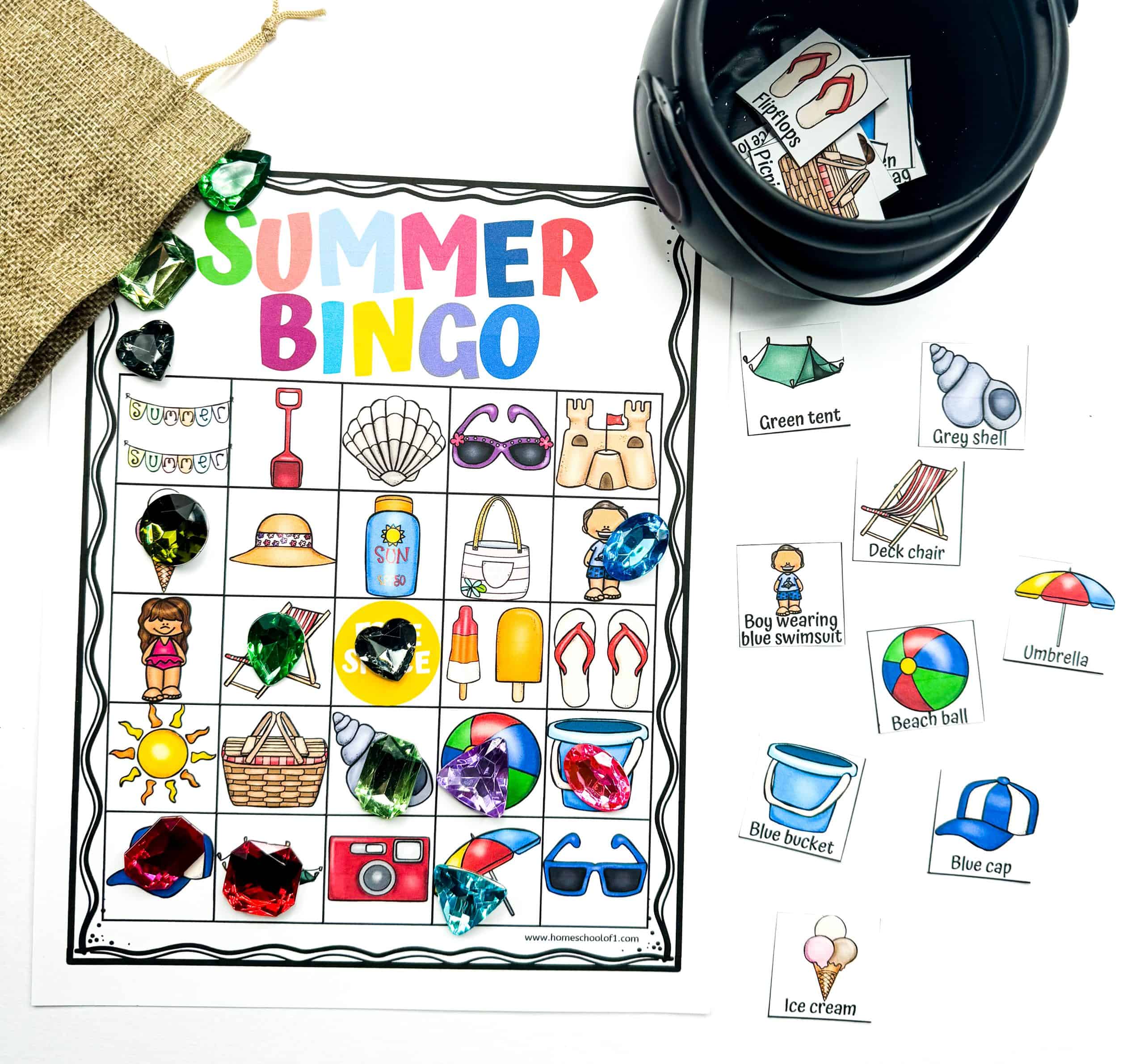 Vibrant summer bingo printable game sheet covered with colorful images like ice cream, sun hats, beach balls, and deck chairs, with sparkly plastic gems used as bingo markers. Surrounded by matching calling cards, this printable summer game for kids is perfect for vacation fun, classroom centers, or backyard playdates.