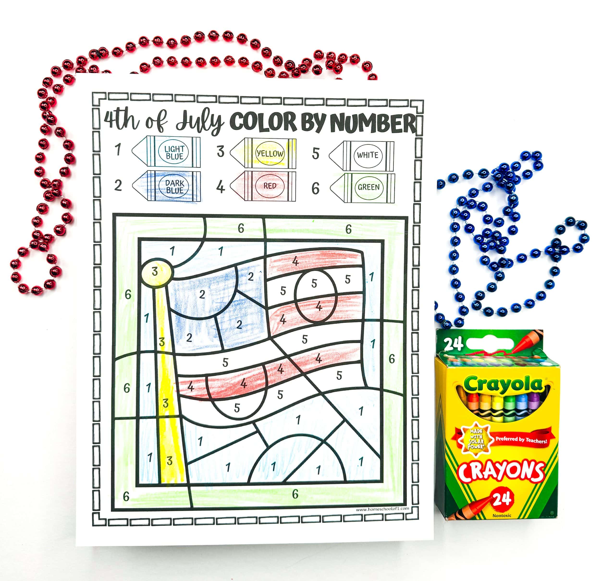 A completed 4th of July color-by-number worksheet displays an American flag on a flagpole, filled in using light blue, dark blue, red, yellow, white, and green according to the numbered crayon key at the top. Red and blue bead necklaces and a 24-pack of Crayola crayons frame the colorful patriotic activity.