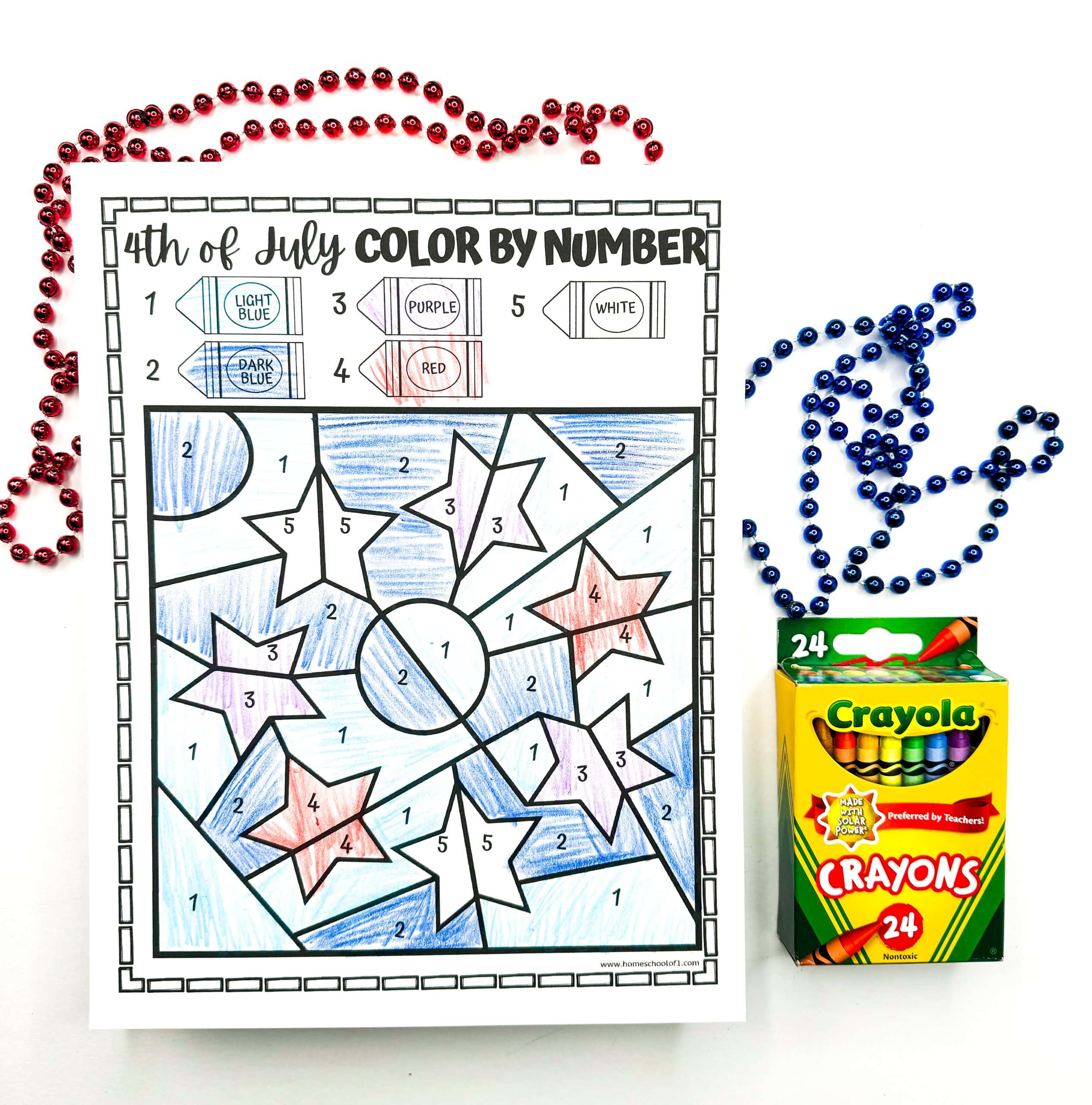A completed 4th of July color-by-number worksheet features a pattern of stars and stripes colored in light blue, dark blue, red, purple, and white according to the crayon key at the top. Red and blue bead necklaces and a Crayola 24-count crayon box frame the patriotic and festive activity sheet.