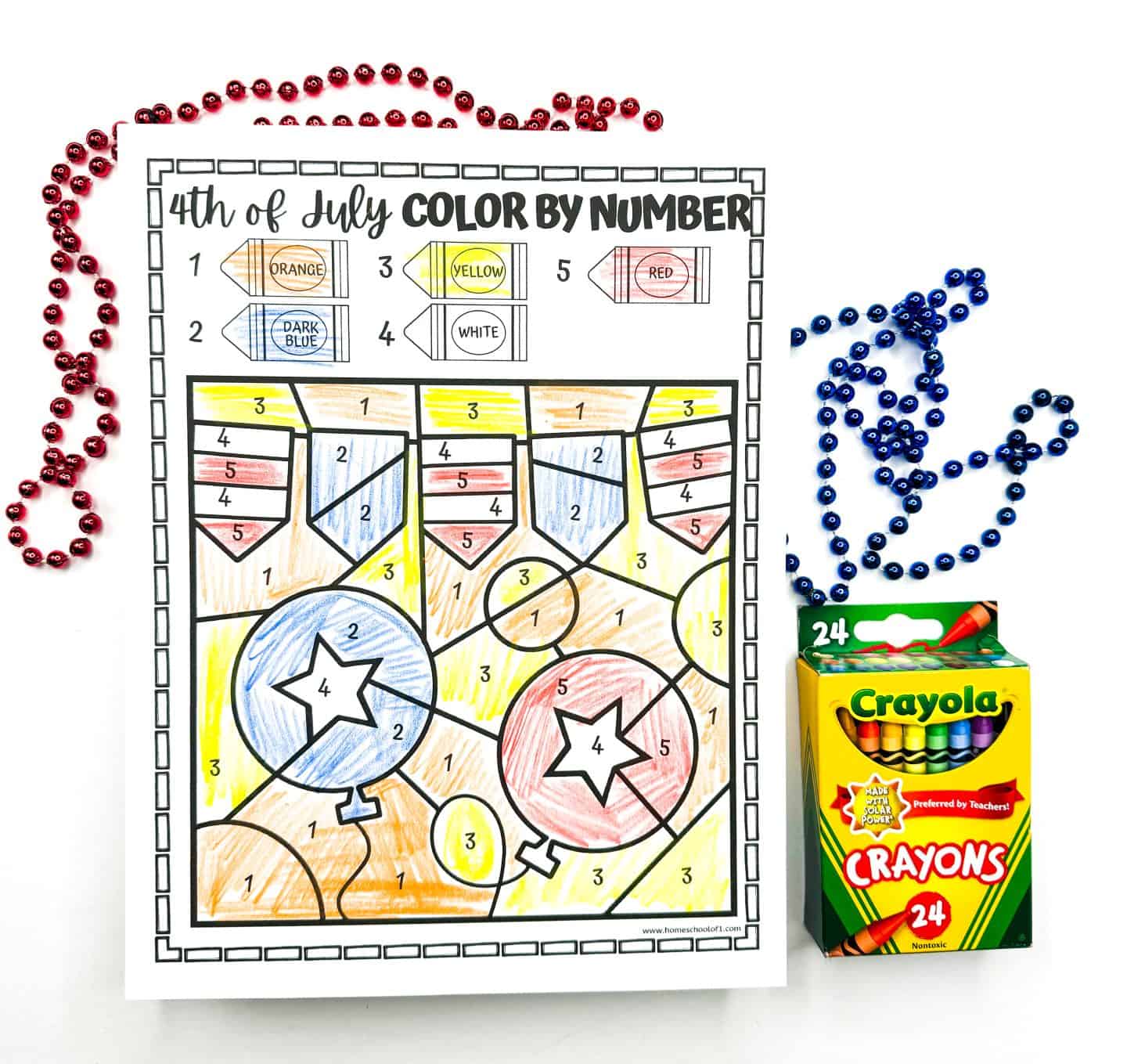 A completed 4th of July color by number printable features a banner and 2 balloon in orange, yellow, dark blue, red and white. Red and blue bead necklaces and a Crayola 24-count crayon box sit next to it.