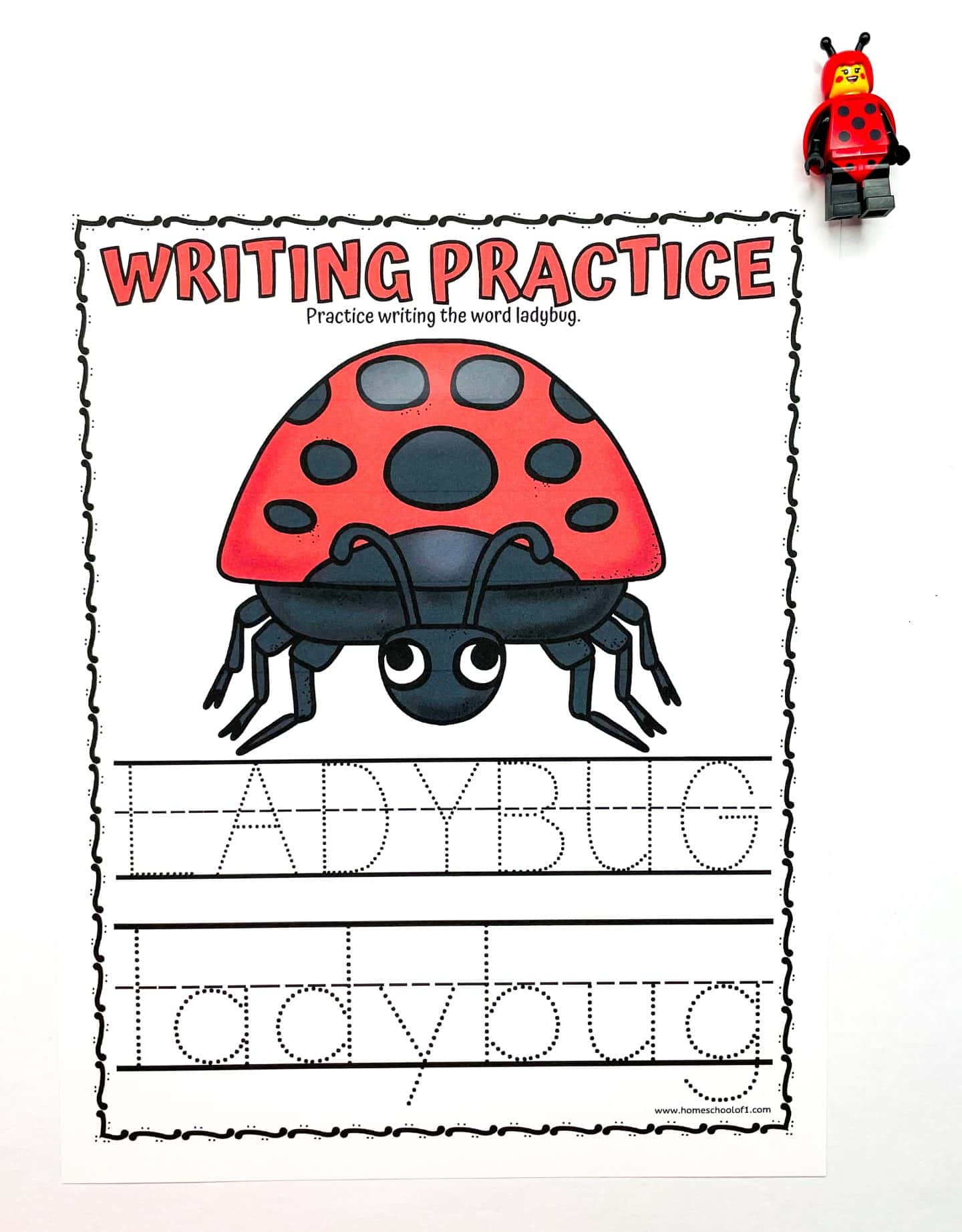  A preschool worksheet titled “Writing Practice” features a large, fully colored cartoon ladybug in red and black. Below it are dotted traceable words “LADYBUG” in uppercase and “ladybug” in lowercase. A small LEGO ladybug figure is placed near the top right corner on a white background.