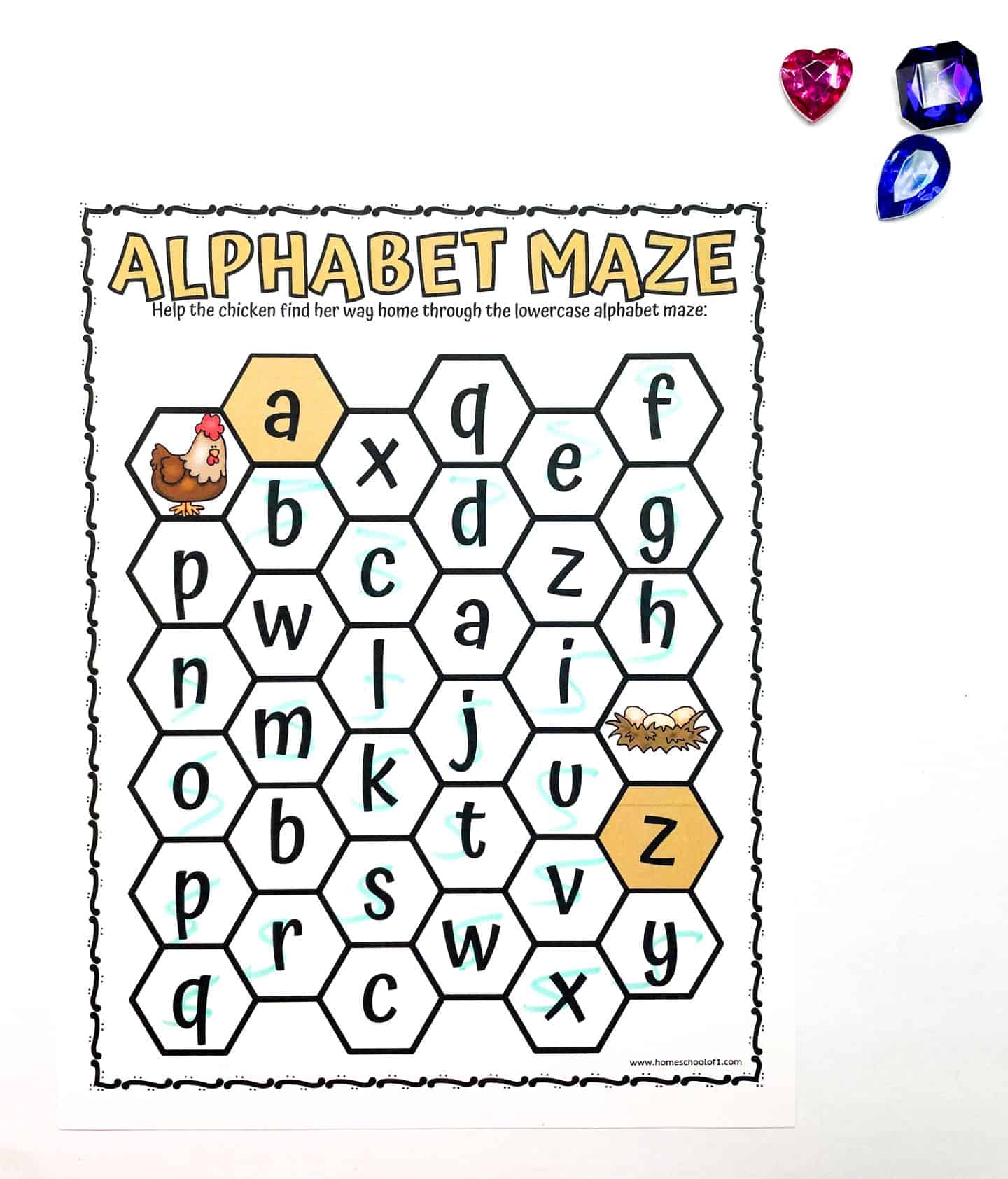 A hexagonal alphabet maze where the goal is to help a chicken reach her nest. Letters in lowercase guide the way. A pink heart and a blue gem sit beside the maze.
