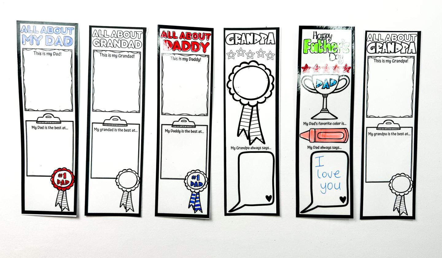 Seven laminated Father’s Day bookmarks lined up, some partially colored. Designs include “All About My Dad,” “All About Grandad,” “All About Daddy,” “Grandpa,” and “Happy Father’s Day,” with fill-in-the-blank sections like “My Dad is the best at…” and “My Dad always says…”—one completed with “I love you” in blue handwriting.