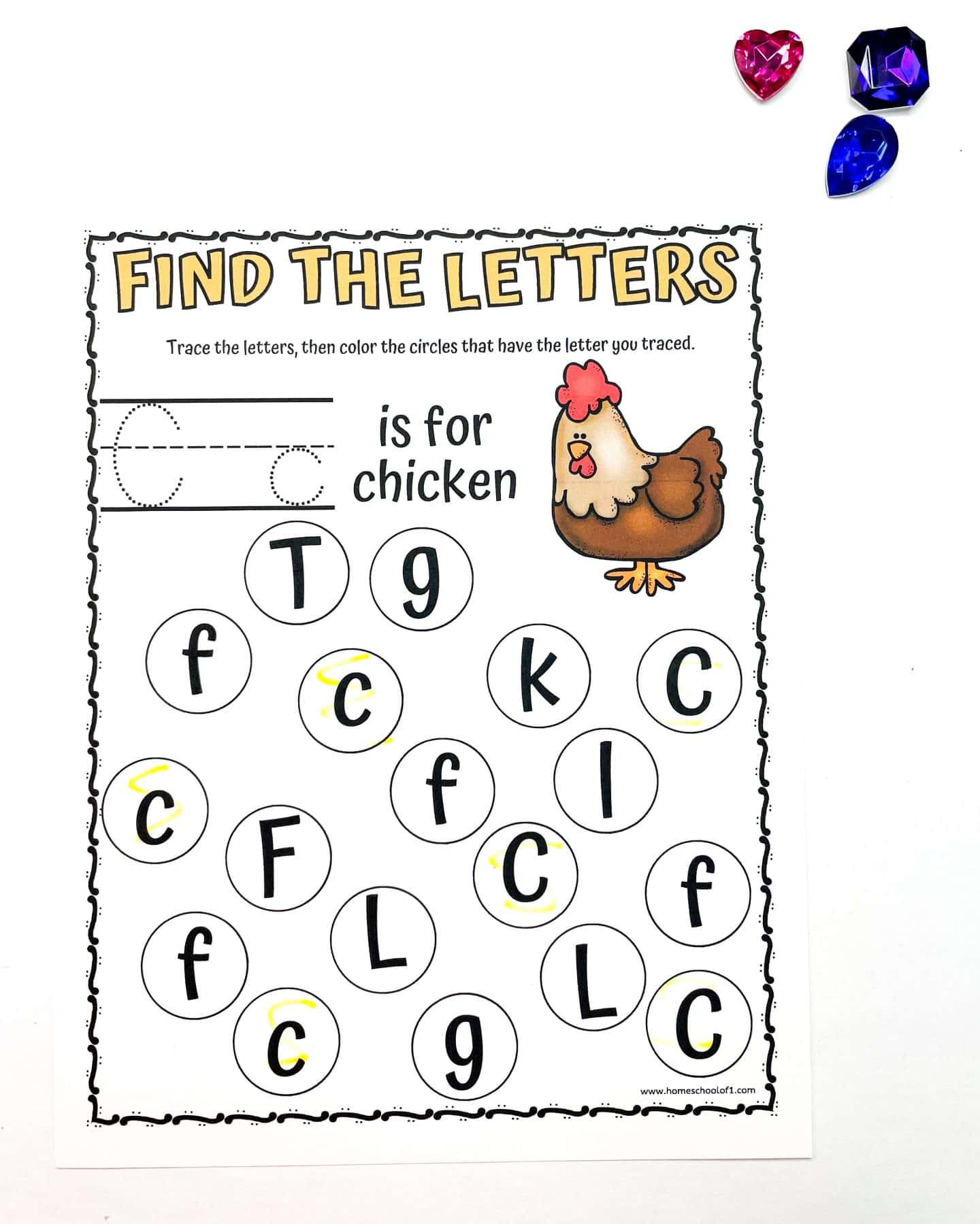 A worksheet titled Find the Letters with a drawing of a chicken. There are circles with various letters, mainly C and F. Some circles are colored yellow. Text at the top says C is for chicken. A pink heart and blue gem are in the top right corner.
