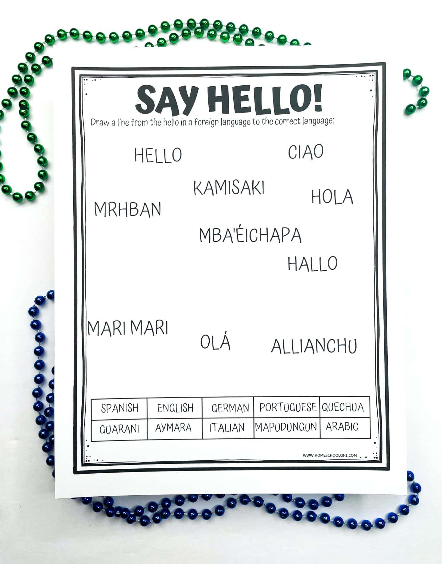 A printable worksheet titled “Say Hello!” asks students to match different greetings with their corresponding languages. Words like “HELLO,” “CIAO,” “HOLA,” “KAMISAKI,” “MBA'ÉICHAPA,” and “ALLIANCHU” appear scattered in the center. At the bottom is a list of languages: Spanish, English, German, Portuguese, Quechua, Guarani, Aymara, Italian, Mapudungun, and Arabic. The activity is surrounded by green and blue bead necklaces as decoration.