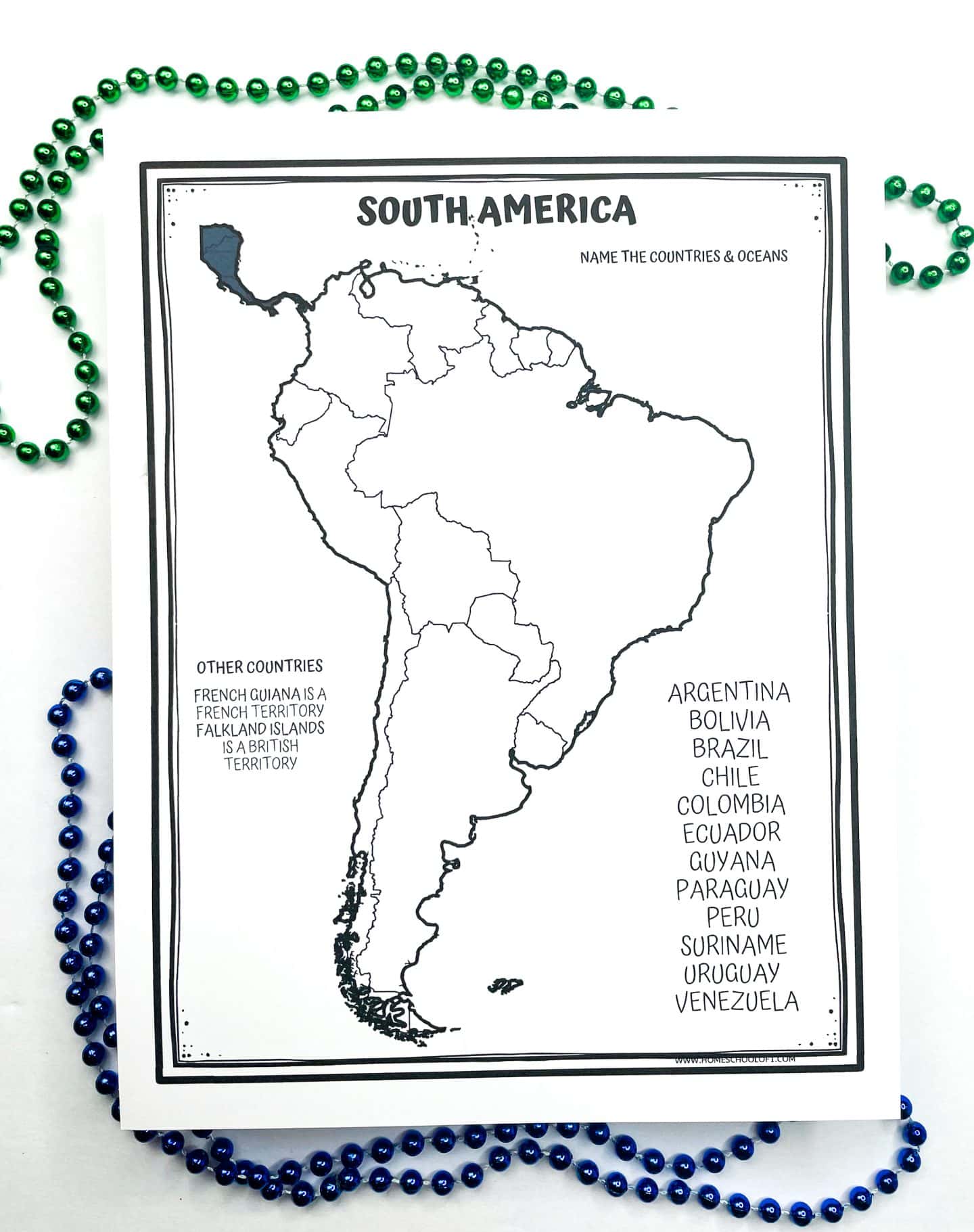 A printable worksheet titled “South America” features an outline map of the continent with country borders but no names filled in. Students are prompted to name the countries and oceans. A side list names all South American countries including Argentina, Brazil, Chile, and others, and notes that French Guiana is a French territory and the Falkland Islands are a British territory. Green and blue bead necklaces surround the worksheet as decoration.