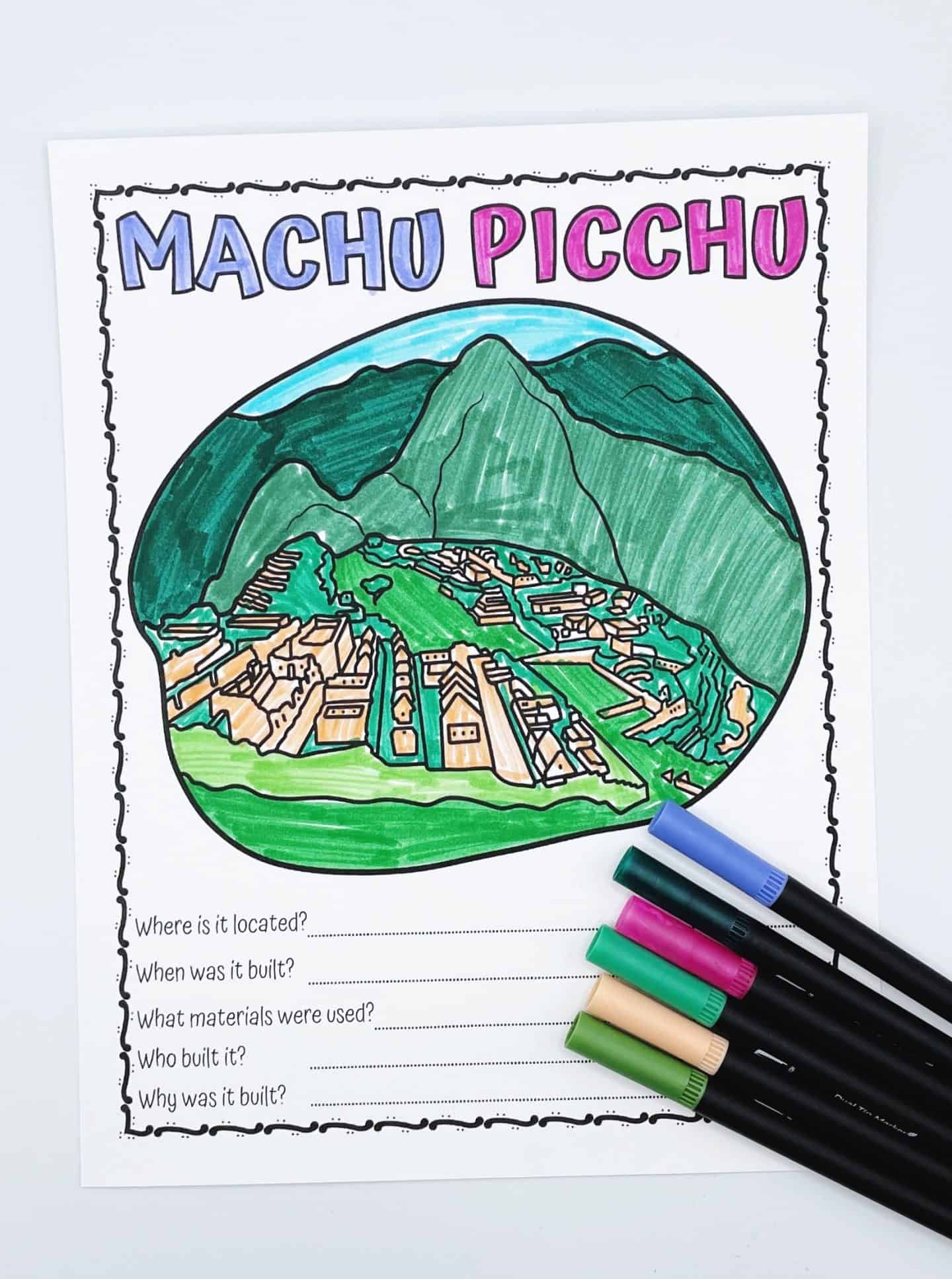 Coloring worksheet of Machu Picchu featuring a hand-colored mountain and ruins scene with labeled questions underneath asking about its location, date built, materials, builder, and purpose. Five uncapped markers in various colors rest beside the sheet.