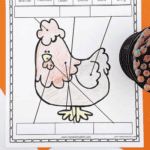 Colorful printable worksheet titled “Parts of a Chicken,” featuring a cartoon chicken with arrows pointing to different labeled body parts including wattle, hackles, beak, comb, claw, and wing. The chicken is partially colored in pink, gray, yellow, and outlined in black, and students are instructed to match the labels to the correct body parts. A container of colored pencils is visible on the side.