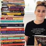 Teen student sitting beside a large stack of Sonlight World History books used in HBL G homeschool curriculum.
