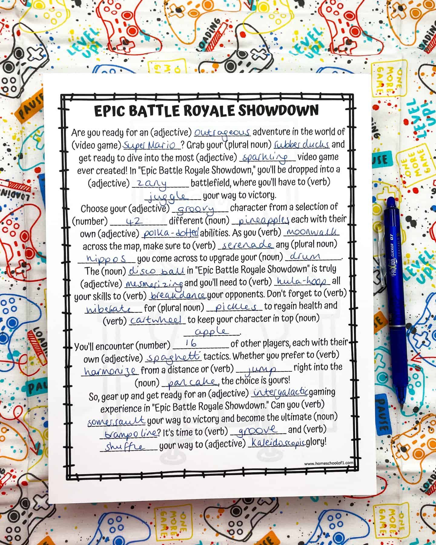 Funny Mad Libs worksheet titled “Epic Battle Royale Showdown,” filled with silly answers like “Super Mario,” “rubber ducks,” “moonwalk,” and “pancake.” The story describes a wild video game-style adventure using creative nouns, verbs, and adjectives. The page is placed on a colorful gaming-themed fabric and accompanied by a blue pen.