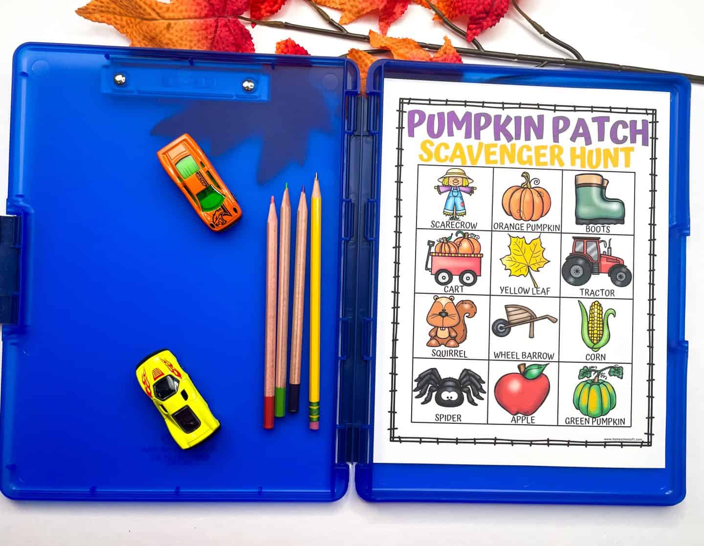 Pumpkin patch scavenger hunt printable displayed in a blue activity case with colored pencils and toy cars, featuring fun fall icons like a scarecrow, orange pumpkin, boots, tractor, apple, and corn. Surrounded by artificial autumn leaves, this kid-friendly scavenger hunt is ideal for classroom use, homeschool units, or fall field trips.

