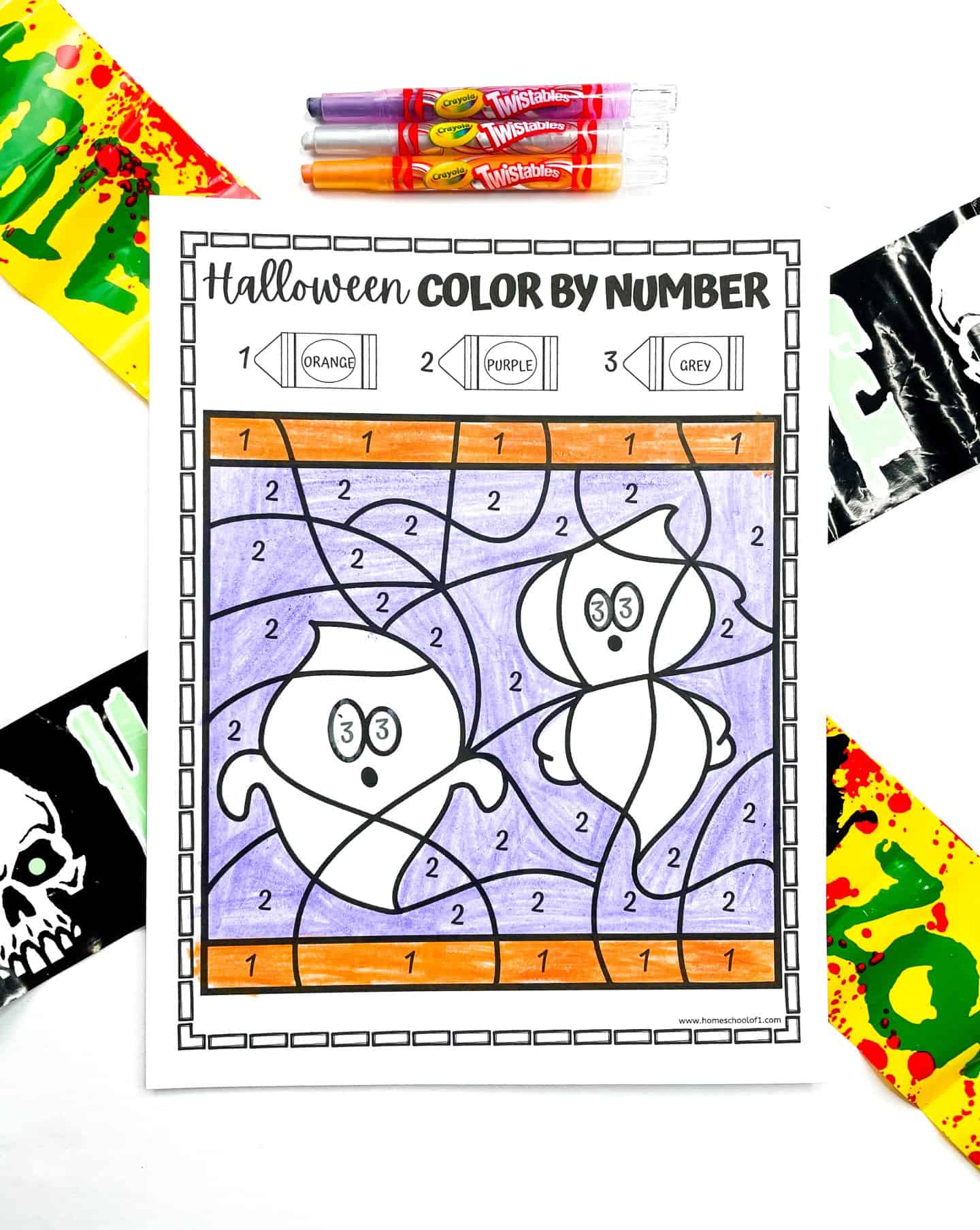  A Halloween color-by-number worksheet features two cute ghosts with a purple background and orange border. The ghosts’ eyes are shaded in grey. The color key at the top includes orange, purple, and grey. Above the page are Crayola Twistables in matching colors. The setup is framed with Halloween caution tape reading “ZOMBIE” and skull-themed graphics, creating a festive spooky vibe.