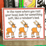 Reindeer scavenger hunt clue card placed in front of books, with festive border and cartoon reindeer illustrations.