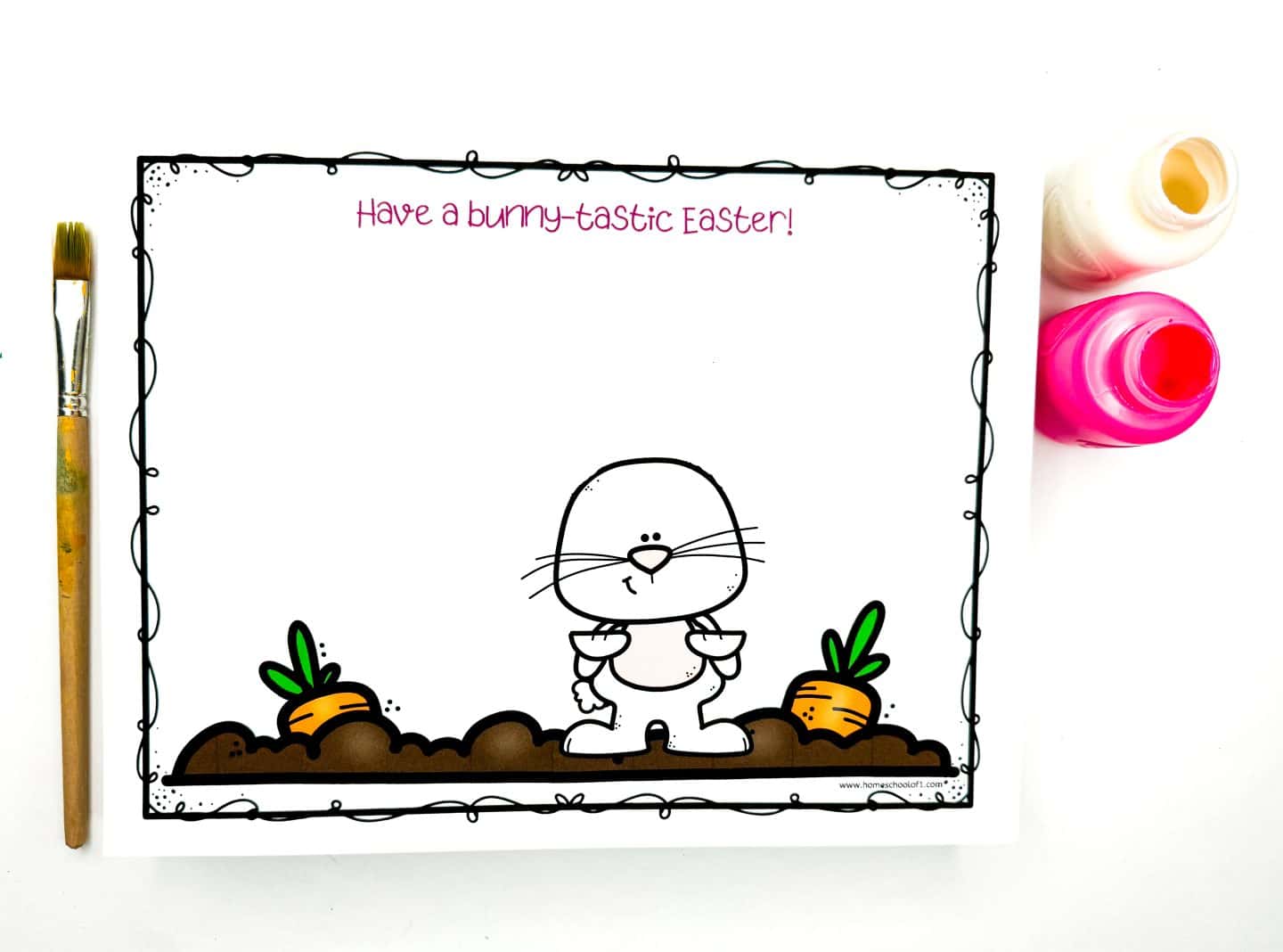 Easter handprint art template featuring a bunny standing between two carrots in a patch of soil with the caption “Have a bunny-tastic Easter!” in pink text at the top. The background is blank, inviting kids to add handprint ears or decorations using the pink and white paint pots and paintbrush shown beside the page.