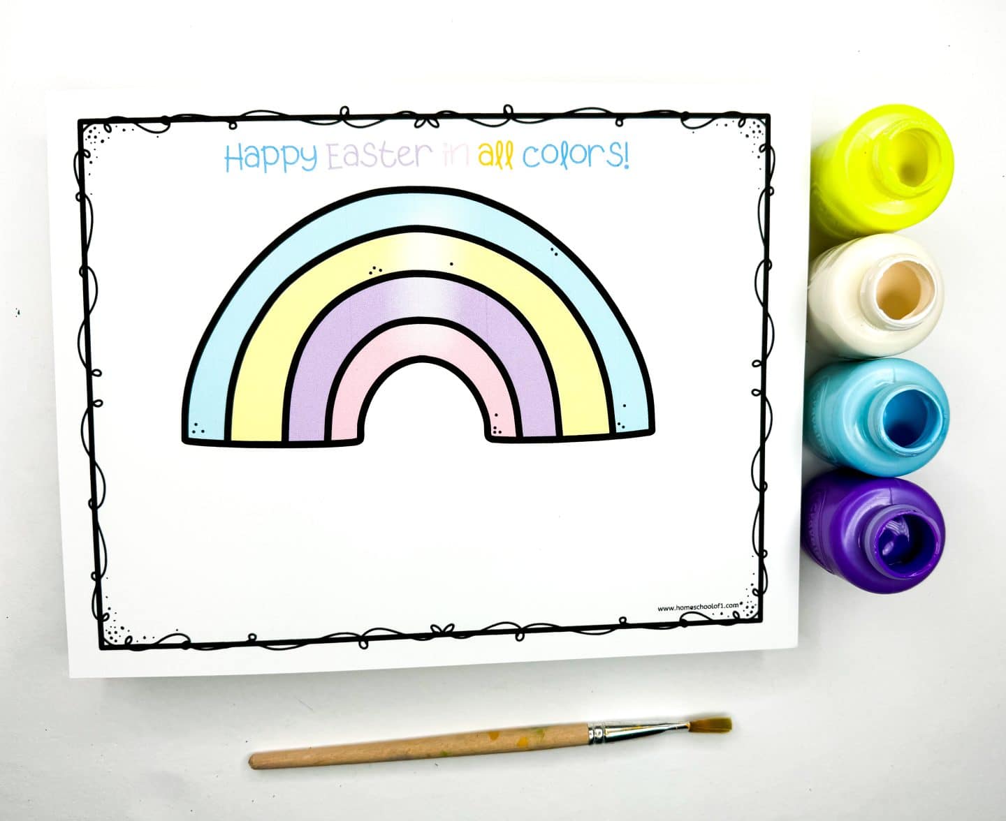 Easter handprint art template featuring a pastel rainbow with the message “Happy Easter in all colors!” written above in blue, pink, and yellow. Four paint pots—yellow, white, teal, and purple—are placed to the right, and a paintbrush lies below the page, ready for decorating with handprints.