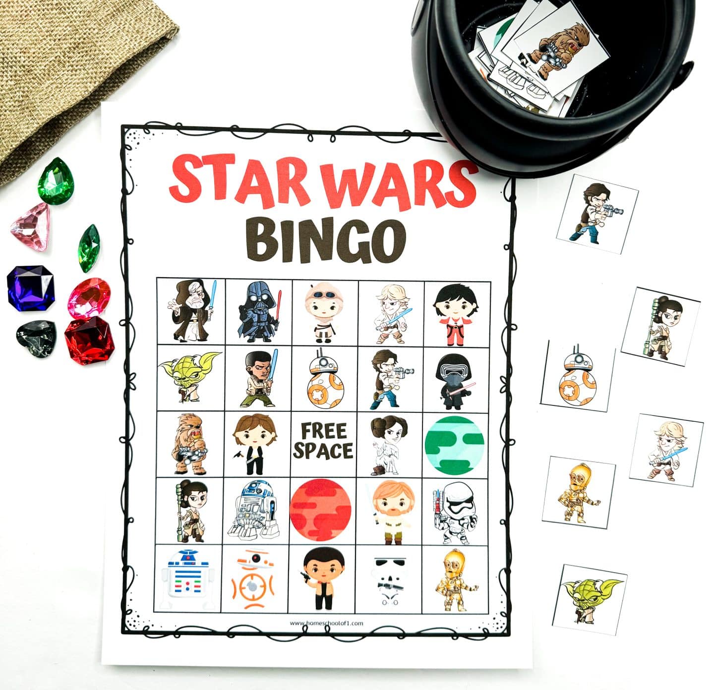 A Star Wars bingo card with various illustrated characters arranged in a 5x5 grid. Surrounding the board are large, plastic gem markers and extra character tiles, ready to be used.


