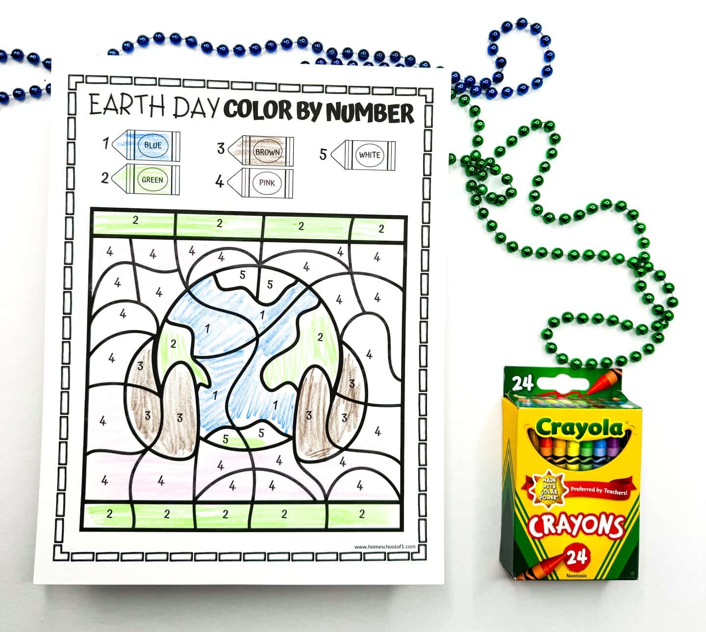 Earth Day themed activity sheet featuring a planet Earth illustration with hands holding it, shaded by matching numbers to colors. The numbers guide the use of blue for oceans, green for land, and brown for hands, promoting Earth awareness. Crayola crayons and colorful beaded necklaces frame the vibrant, kid-friendly educational page.