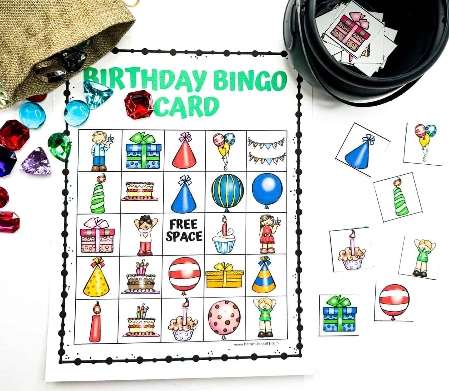 Colorful "Birthday Bingo Card" game featuring a 5x5 grid with festive illustrations like balloons, cakes, party hats, candles, presents, and a “FREE SPACE” in the center. Surrounding the card are cut-out bingo tiles and bright gem-like markers spilling from a burlap pouch and black container.

