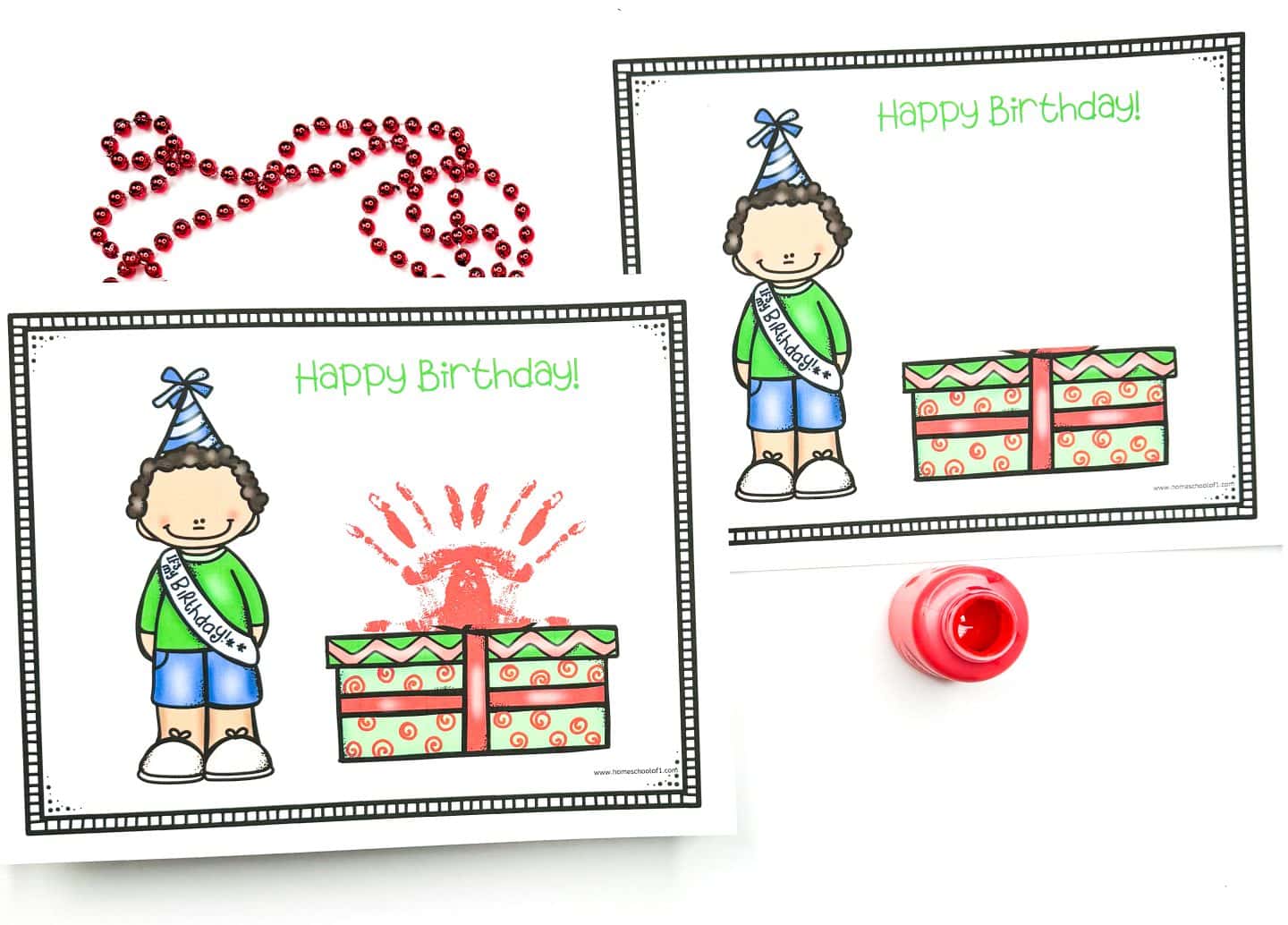 Birthday handprint printables featuring a cartoon boy in a party hat and "Birthday Boy" sash standing next to a stack of wrapped gifts, with “Happy Birthday!” written in green text. One version includes a red handprint on top of the presents as a fun craft element, while the other is blank for personalization. Red beads and red paint are also shown for creative inspiration.