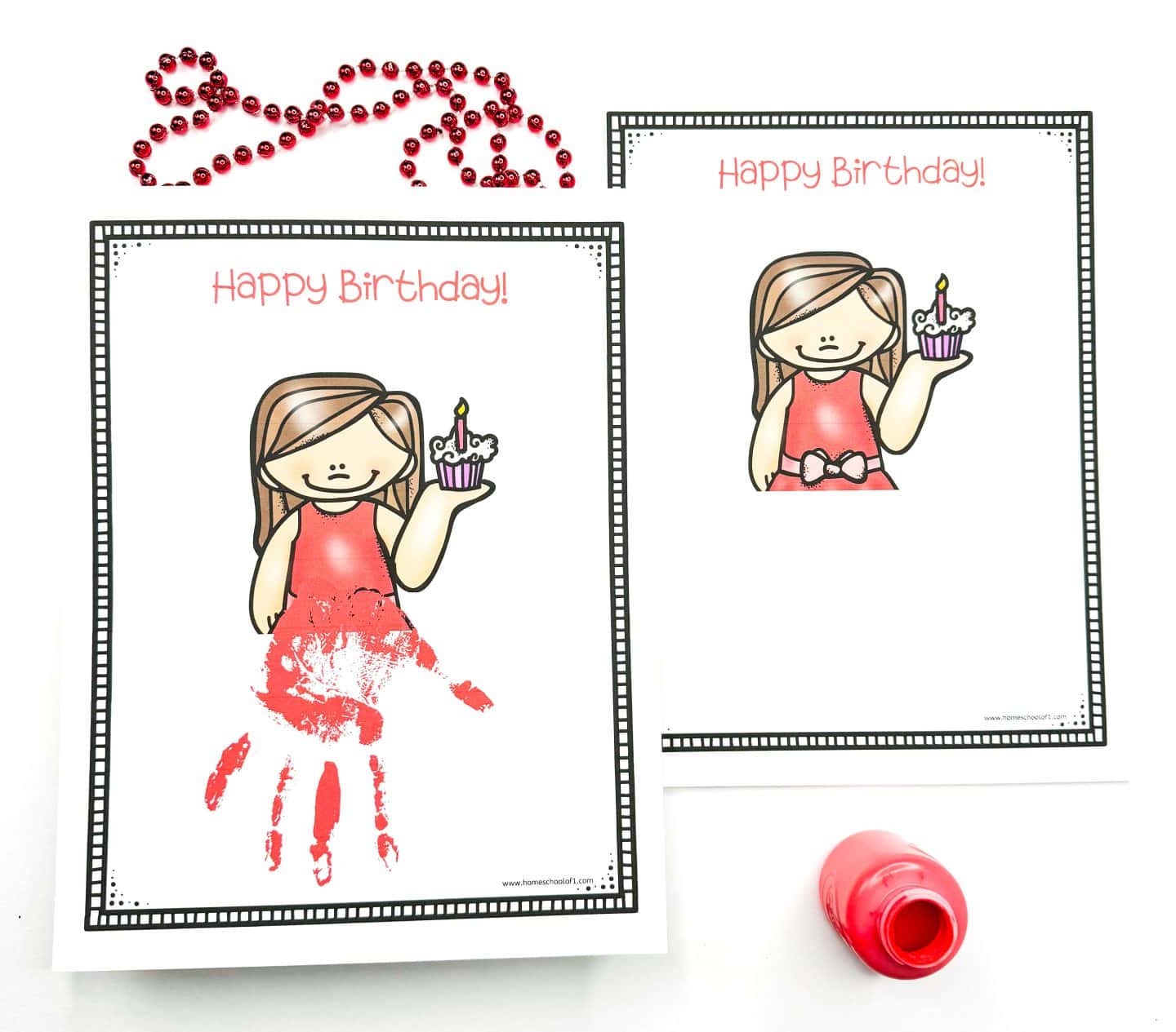 Birthday handprint art printable featuring a cartoon girl in a red dress holding a cupcake with a lit candle, framed by the words “Happy Birthday!” One sheet includes a red handprint that extends her dress into a personalized design, while the second is left blank for DIY creativity. Red beads and a red paint bottle complete the fun birthday craft setup.

