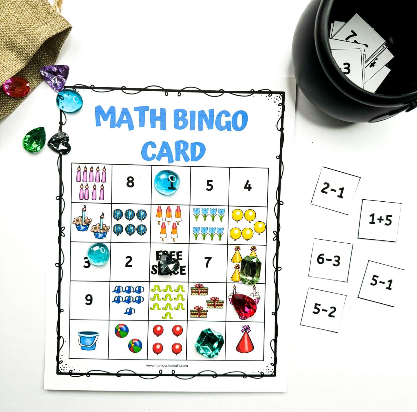 Colorful printable math bingo card for kids with a 5x5 grid filled with numbers and party-themed images like candles, balloons, presents, and cupcakes. Plastic gem markers are placed on some squares, and a black container holds math problem flashcards like “2-1” and “5-2.” Additional gems and flashcards are scattered nearby.