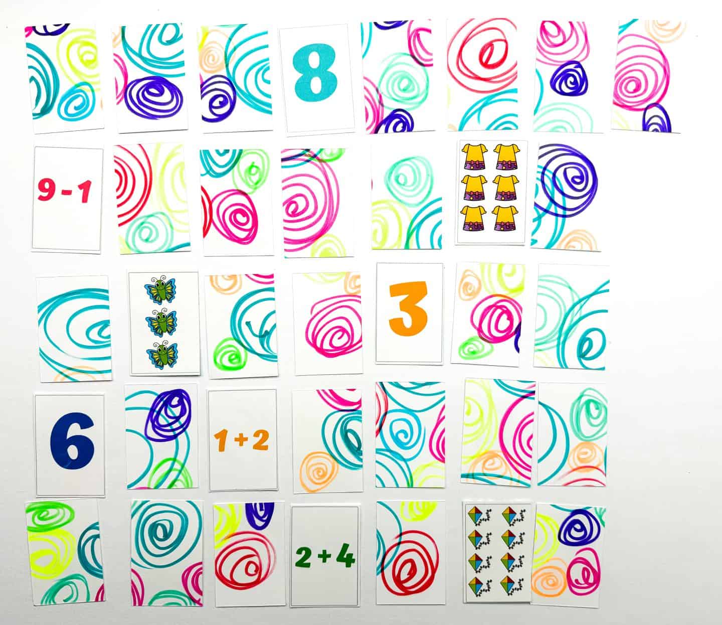 A colorful layout of a math memory game in progress, featuring cards with bright swirly patterns on the backs and a mix of revealed cards showing numbers (like 3, 6, 8), math equations (like 2+4, 9-1, 1+2), and object groups (such as shirts, butterflies, and kites). Designed for engaging math practice through matching.