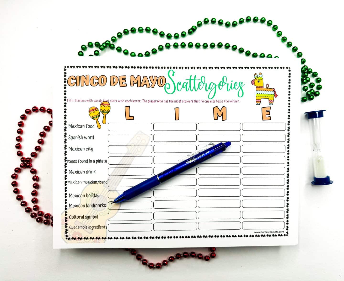 Cinco de Mayo Scattergories sheet with the letter 'LIME' filled out, ready for word association fun, accented with red and green Mardi Gras beads, a blue pen, and an hourglass