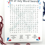 Printable Fourth of July word search puzzle with red, white, and blue fireworks design at the top and festive bead necklaces around the page. The word search grid contains patriotic terms like “Independence,” “Freedom,” “Liberty,” “Justice,” “Stars,” “Stripes,” and “Declaration,” which are partially circled in green. Decorative red, white, and blue stars appear in the corners, and the bottom of the image says “Fourth of July Word Search” in bold red, white, and blue letters.