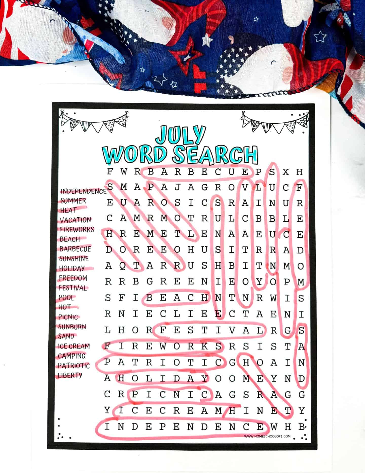 A July-themed word search printable with a patriotic scarf in the background. The word search includes terms like Independence, Summer, Heat, Vacation, Fireworks, Beach, Barbecue, Sunshine, Holiday, Freedom, Festival, Pool, Hot, Picnic, Sunburn, Sand, Ice Cream, Camping, Patriotic, and Liberty, all of which are circled in pink. The worksheet features playful banners drawn in the top corners and a bright 'July Word Search' title colored in teal lettering.