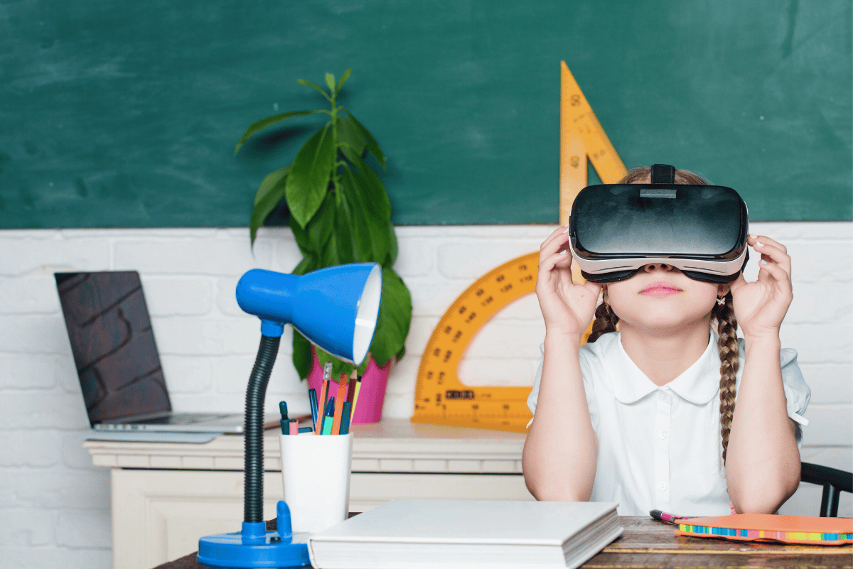 Young girl using virtual reality headset in a homeschool setup with books, school supplies, and a chalkboard in the background.