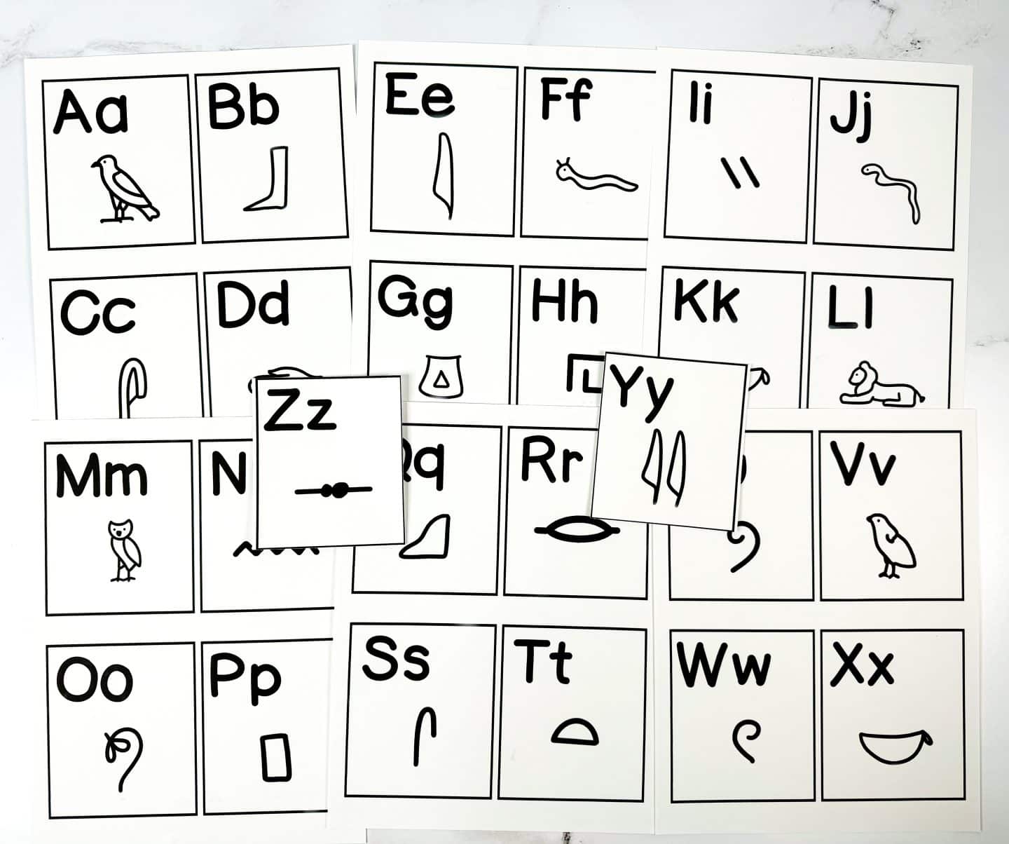 Printable alphabet flashcards matching each letter of the English alphabet (A–Z, uppercase and lowercase) with a corresponding Egyptian hieroglyph symbol. Each card includes a large, bold letter and a clear black-and-white hieroglyph illustration, featuring symbols like birds, snakes, reeds, and tools.

