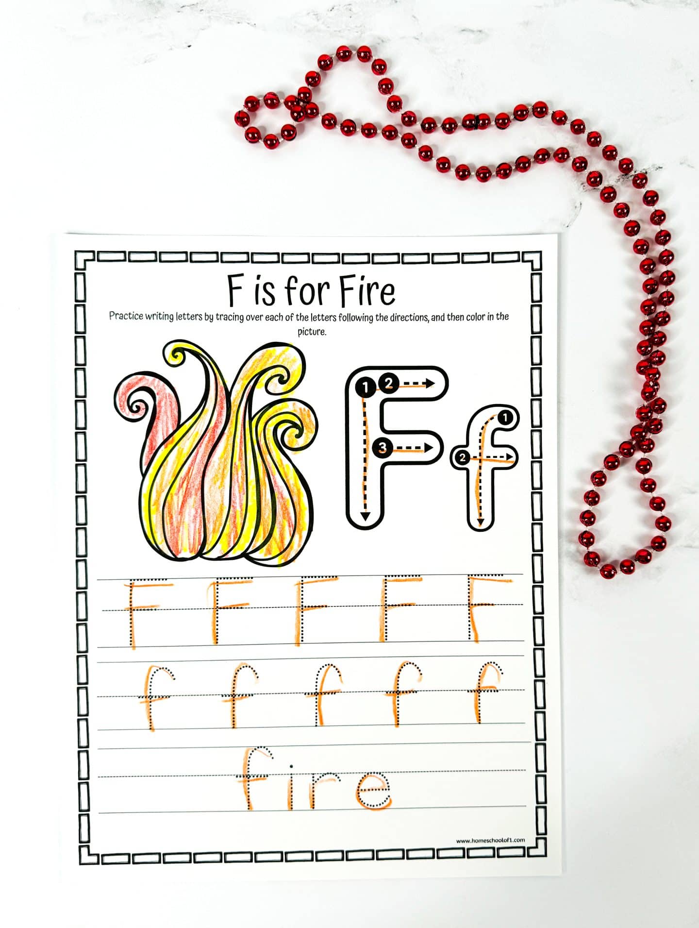 “F is for Fire” tracing worksheet for kids featuring a large colored flame illustration and step-by-step guides to trace uppercase and lowercase “F.” Includes practice lines for writing the letter and the word “fire” in dotted tracing format.