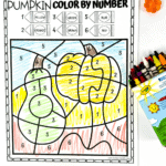 Pumpkin color-by-number page mostly colored in yellow and green, next to a crayon box and small fall decor.