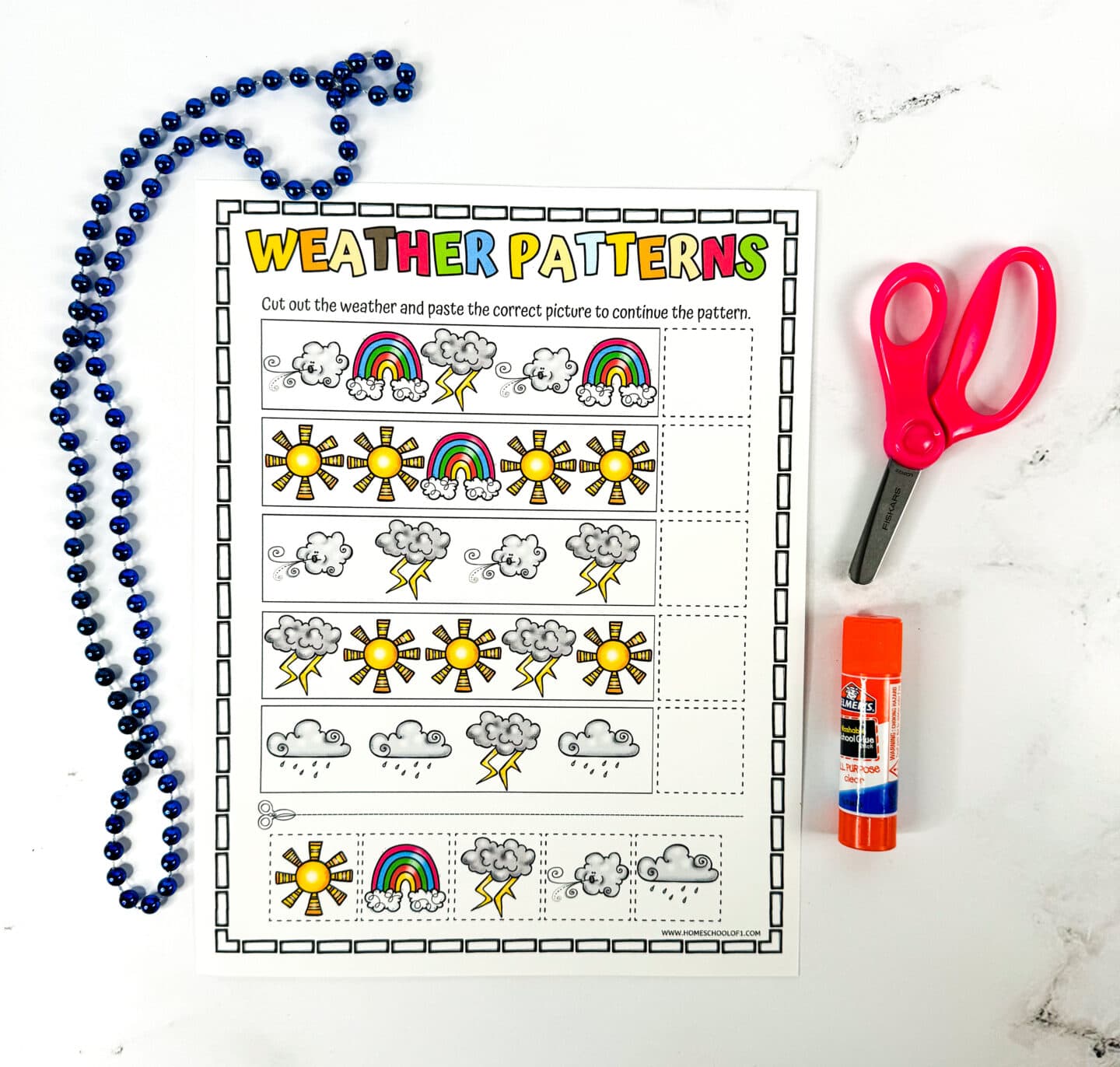 Weather patterns printable activity sheet for kids featuring rows of colorful weather icons—sun, rainbow, clouds, lightning, and rain—used to complete visual patterns. The title "Weather Patterns" is in bold multicolor text, with instructions to cut and paste the correct image. A red pair of scissors, a glue stick, and a blue bead necklace are placed around the worksheet.