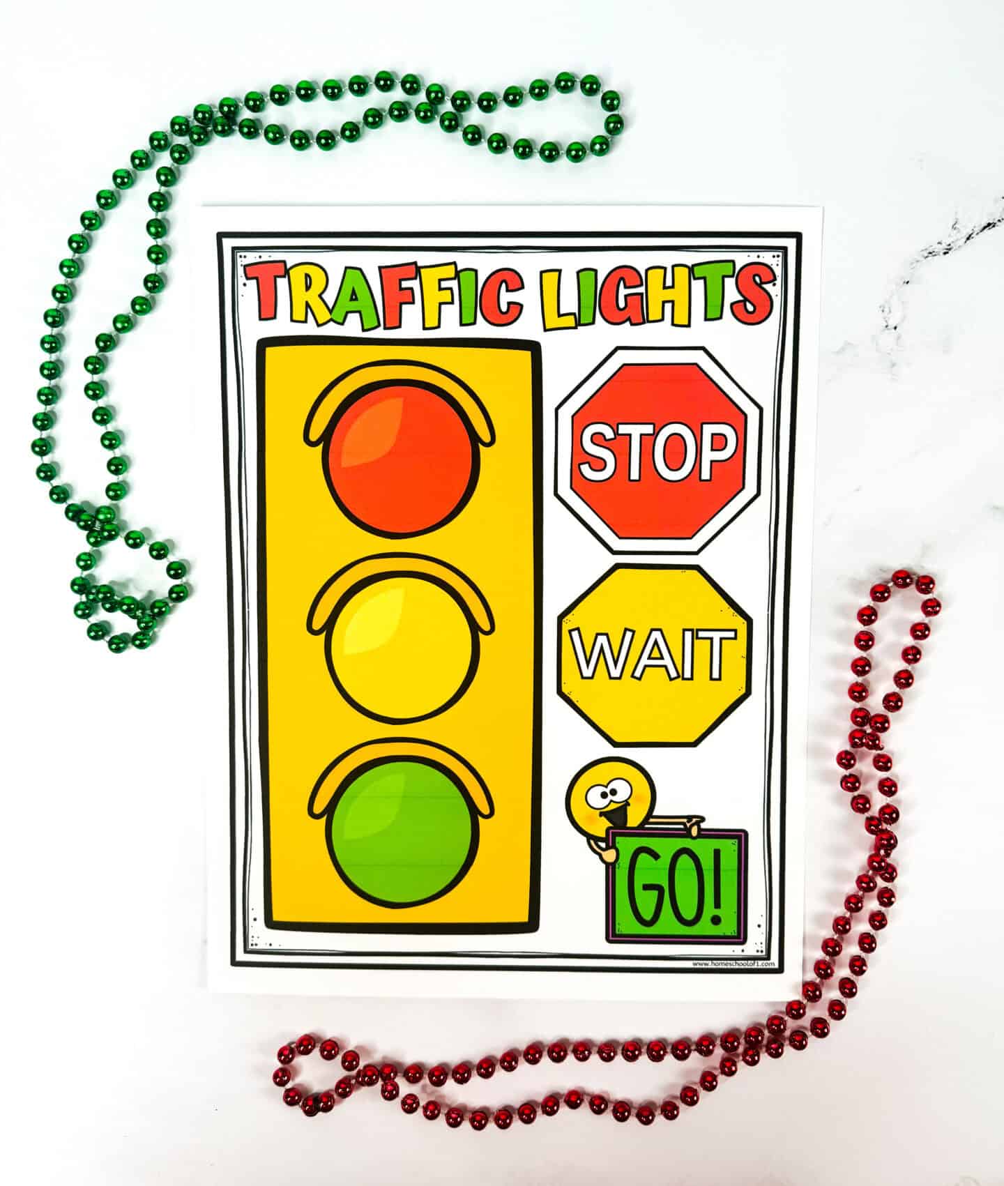 A colorful educational poster titled "Traffic Lights," designed for kids. It features a vertical traffic light with red, yellow, and green circles on the left, and matching labeled signs on the right: a red octagon with "STOP," a yellow hexagon with "WAIT," and a green rectangle with "GO!" held by a cheerful cartoon figure. Red and green bead necklaces frame the poster, adding a playful touch.