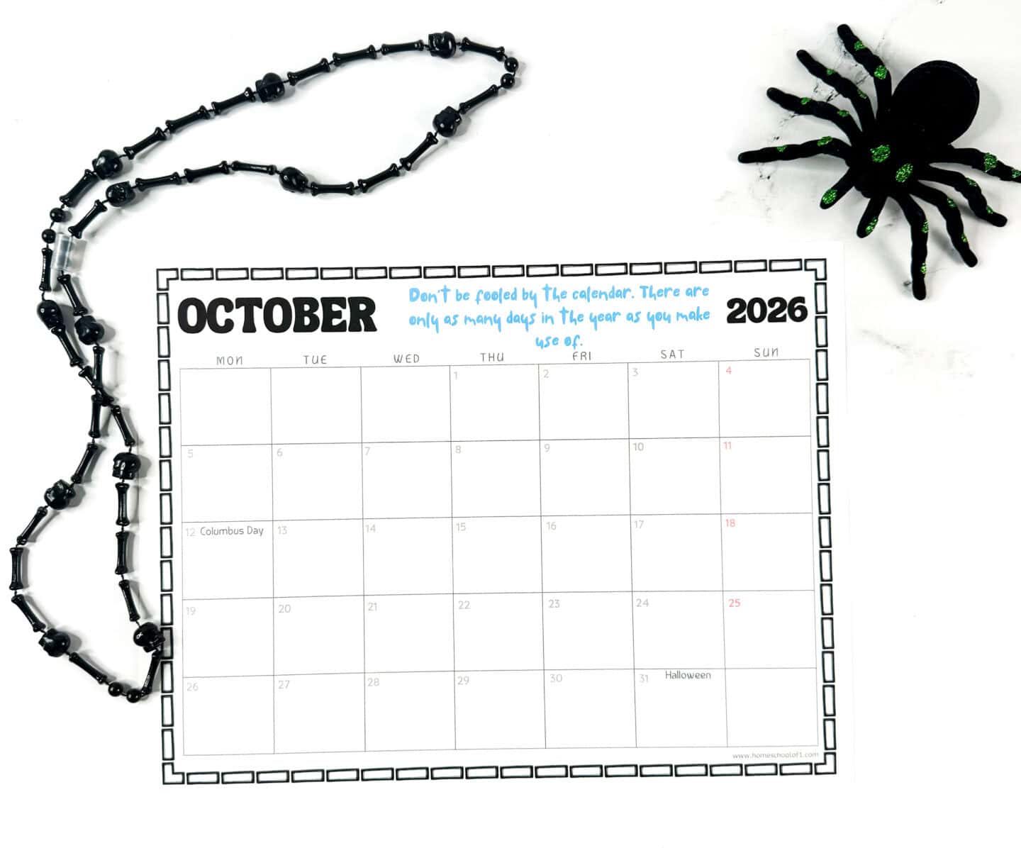 October 2026 printable calendar page with Columbus Day and Halloween highlighted, decorated with black bead garland and a green glitter spider.
