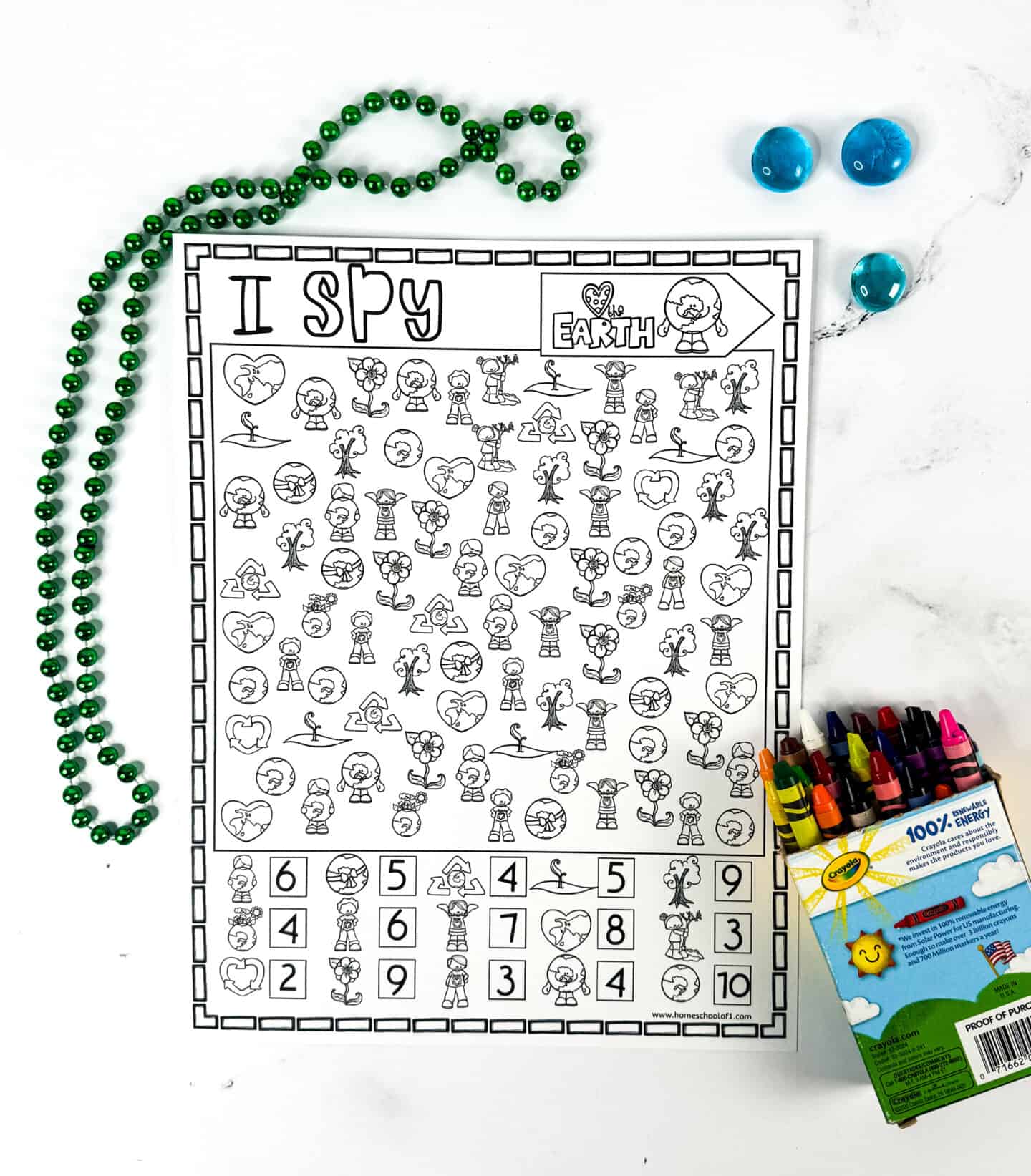 Completed Earth Day I Spy answer sheet with image counts listed at the bottom. Surrounded by crayons and beads, the sheet includes eco-friendly illustrations like hearts with the Earth, kids hugging the globe, and trees, making it a great solution guide for educators.