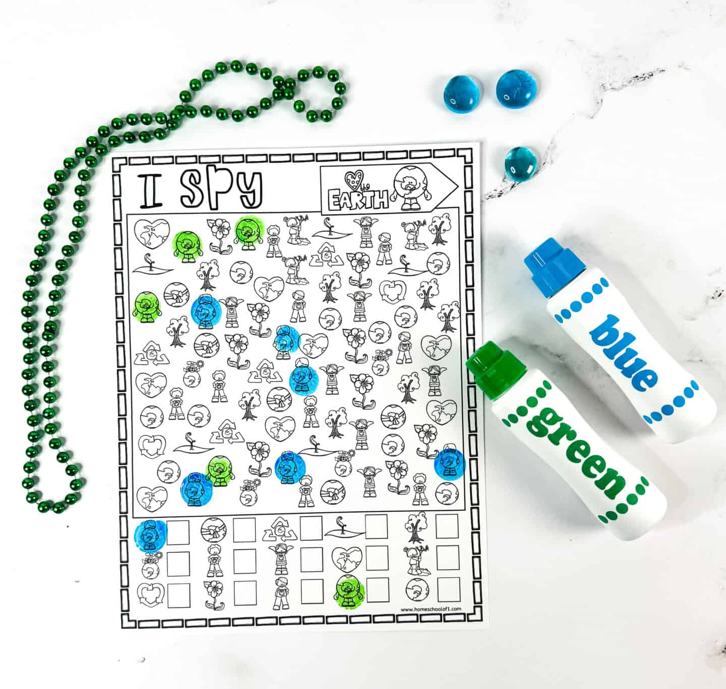 Black and white Earth Day I Spy worksheet marked with blue and green dot markers, showing various Earth-friendly images like kids planting trees, globes, and recycling logos. A great hands-on printable for Earth Day classroom fun or home learning.