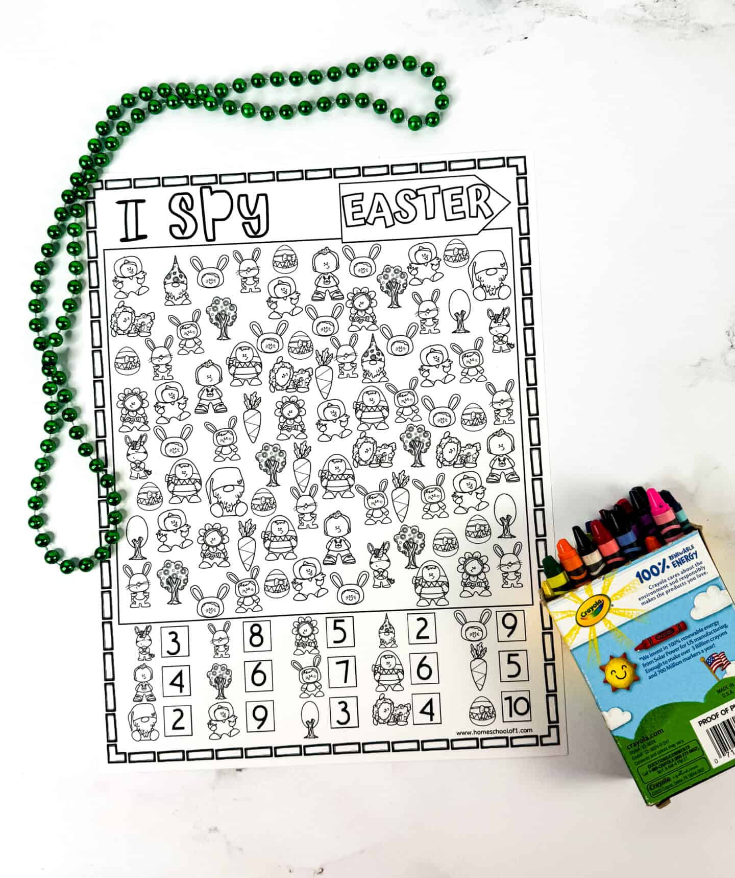 A black-and-white "I Spy Easter" coloring page features cute illustrations like Easter eggs, bunnies, flowers, carrots, trees, and children in costumes. The sheet includes numbers for each icon to count, and it's paired with green beads and a colorful crayon box.