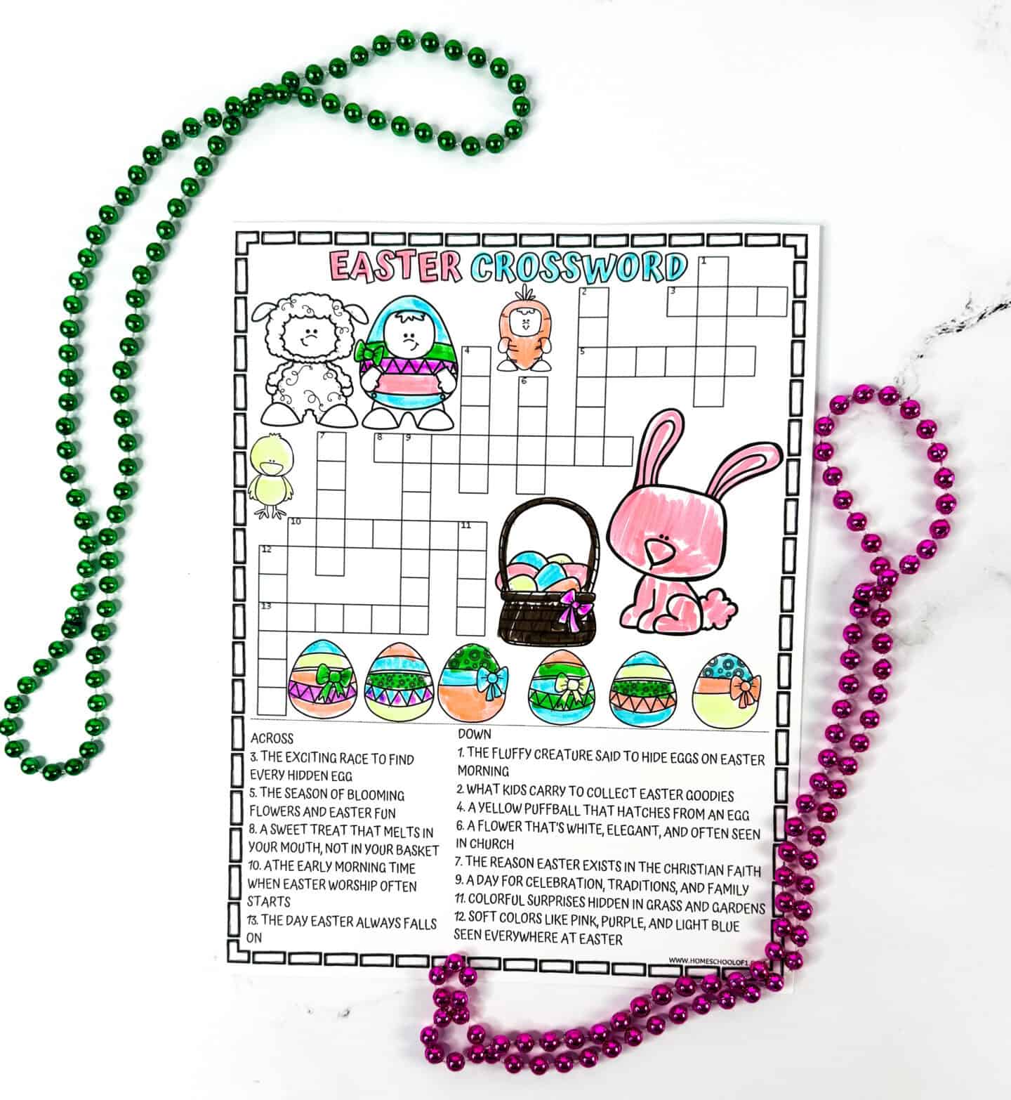 Partially completed Easter crossword puzzle for kids, with cute colored drawings of a pink bunny, Easter basket with eggs, spring animals, and decorative eggs. The puzzle grid is only partially filled, and it's framed by festive green and pink beads on a marble surface.