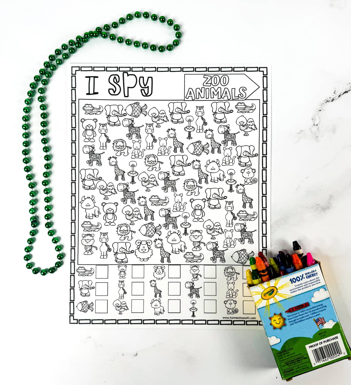 A black and white “I Spy Zoo Animals” printable worksheet featuring cute cartoon animals such as elephants, giraffes, lions, crocodiles, and flamingos. The activity includes a visual key at the bottom for counting each animal, and it's placed on a white surface with a green beaded necklace and an open box of Crayola crayons nearby.