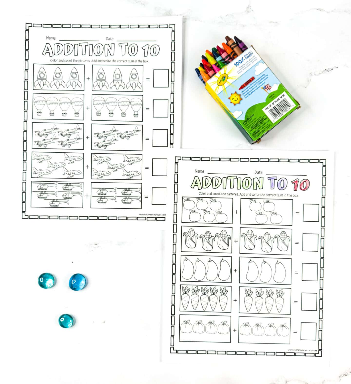 Two printable addition to 10 worksheets for kindergarten featuring rockets, hot air balloons, planes, and fruits with a crayon box nearby.