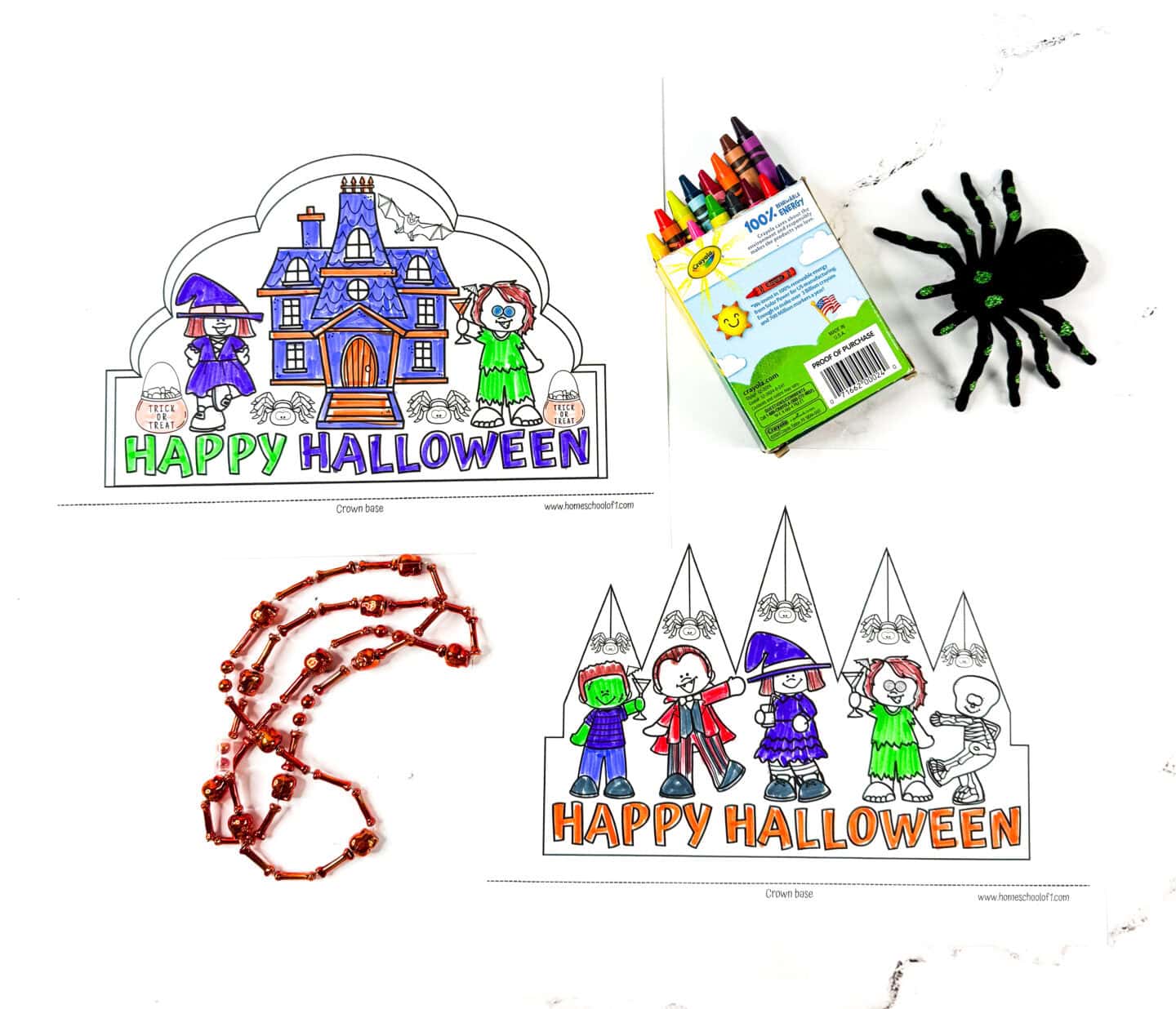 Color-in Halloween crown printables partially completed, shown with crayons, a green-and-black spider toy, and Halloween beads on a white background.