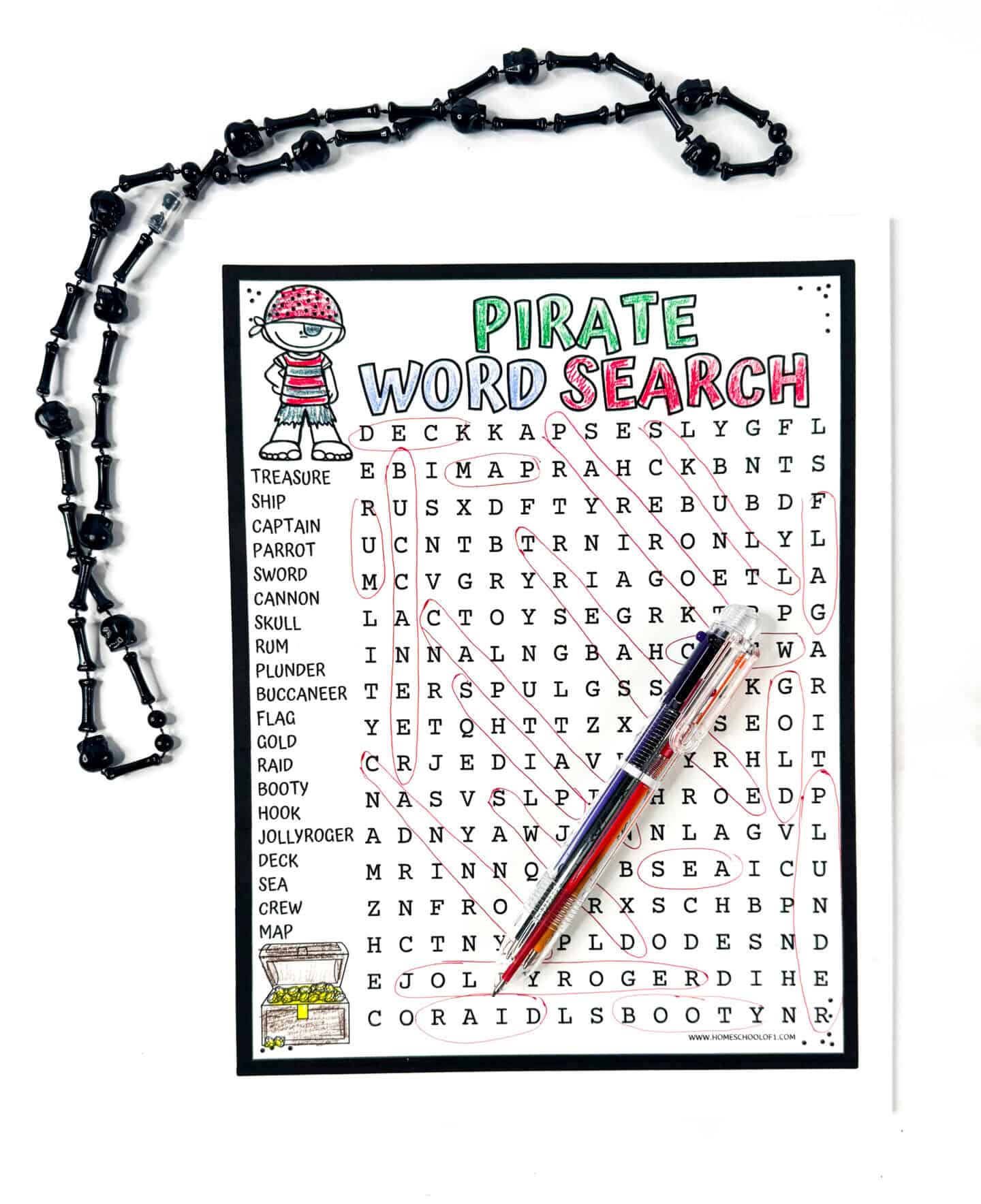 Completed pirate word search with words circled in red, cartoon pirate, treasure chest, black beaded necklace, and pen.